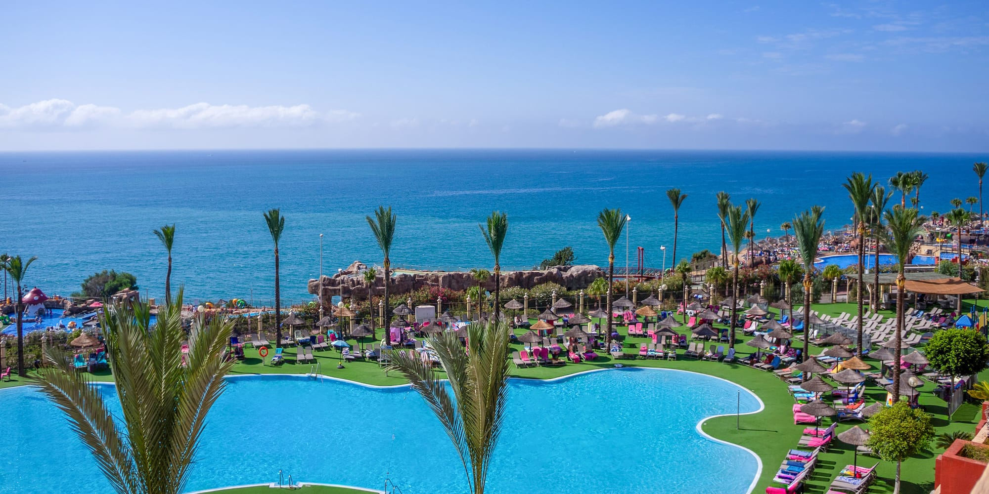 a pool with palm trees and a beach and a body of water