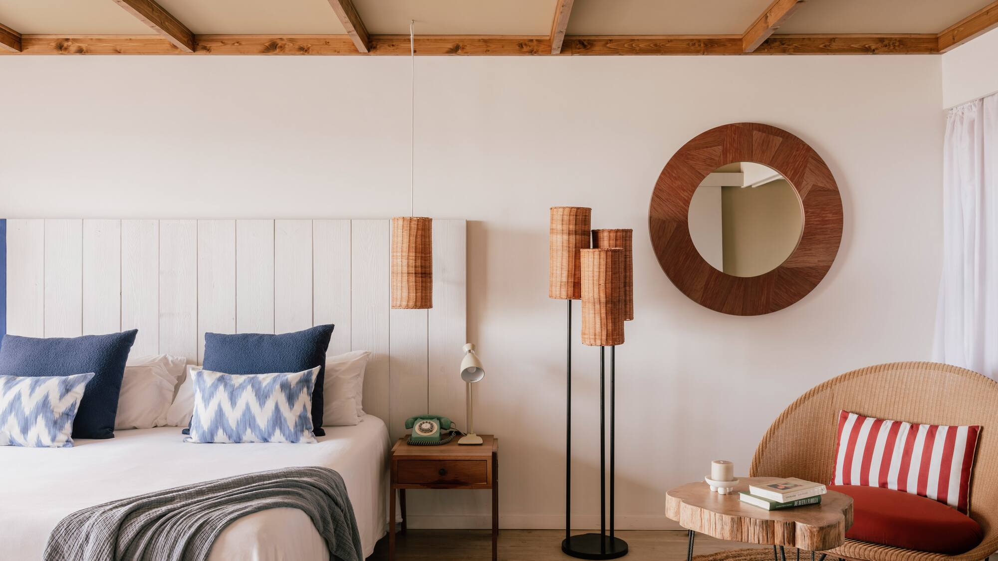 Bohemian bedroom: white bed, blue pillows, wooden ceiling, rattan decor.