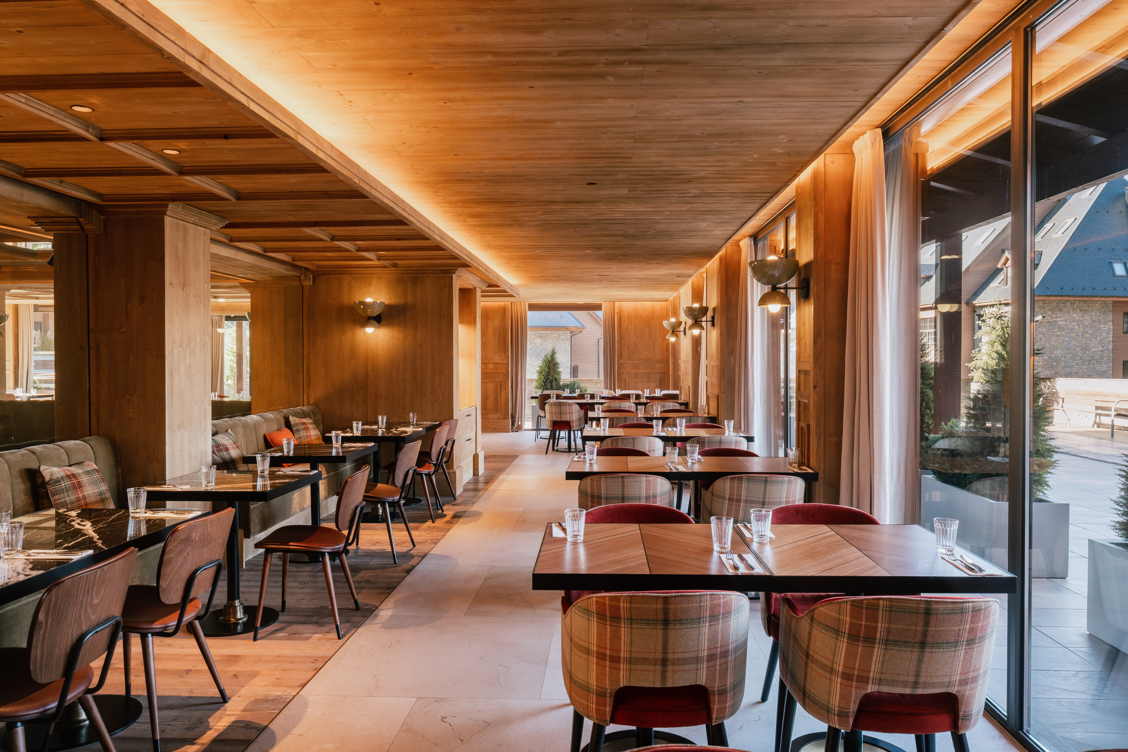 Comedor de madera moderno, mesas preparadas, sillas de diseño, ventanales.