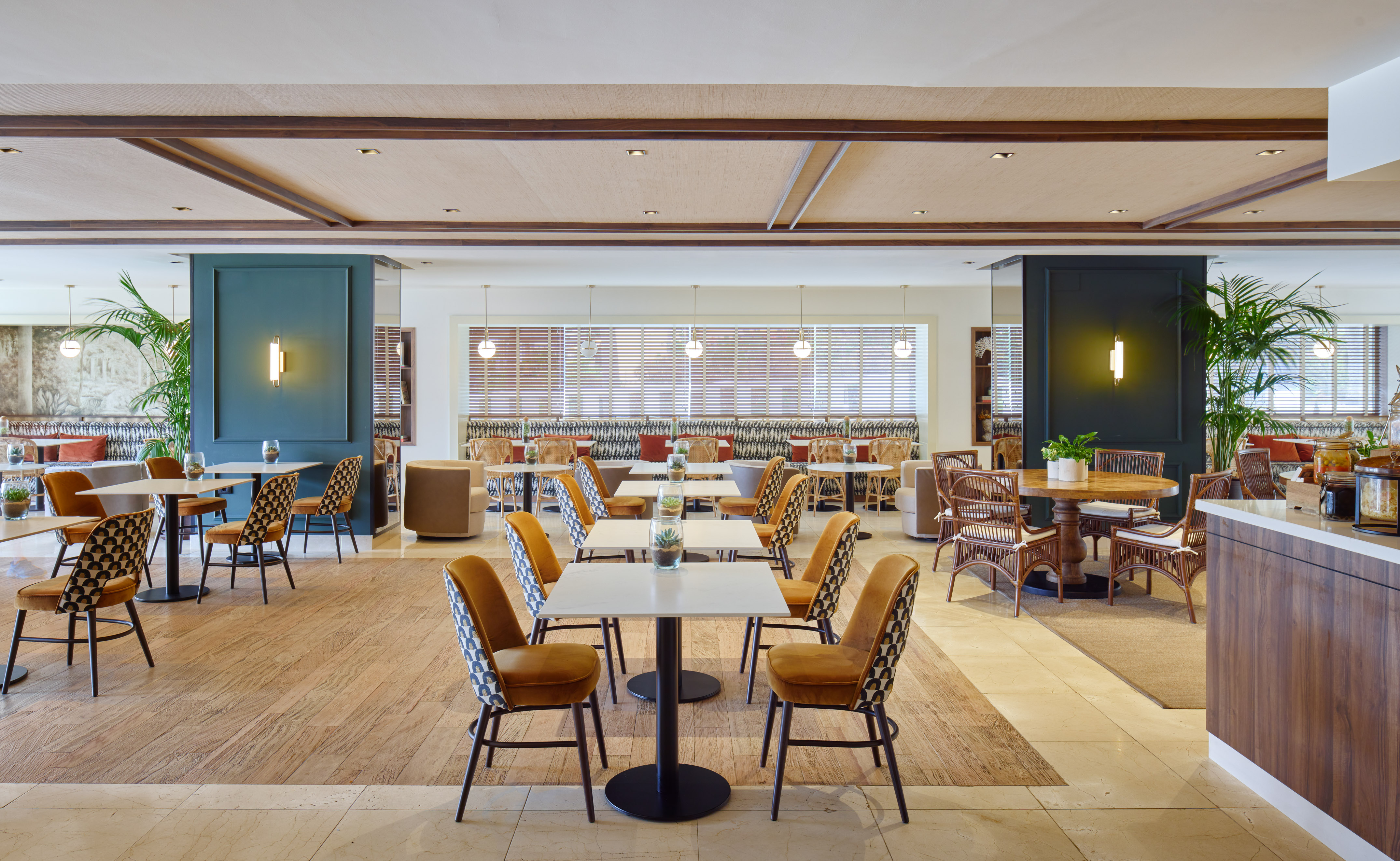 Stylish hotel restaurant interior with modern furniture and tropical plants.