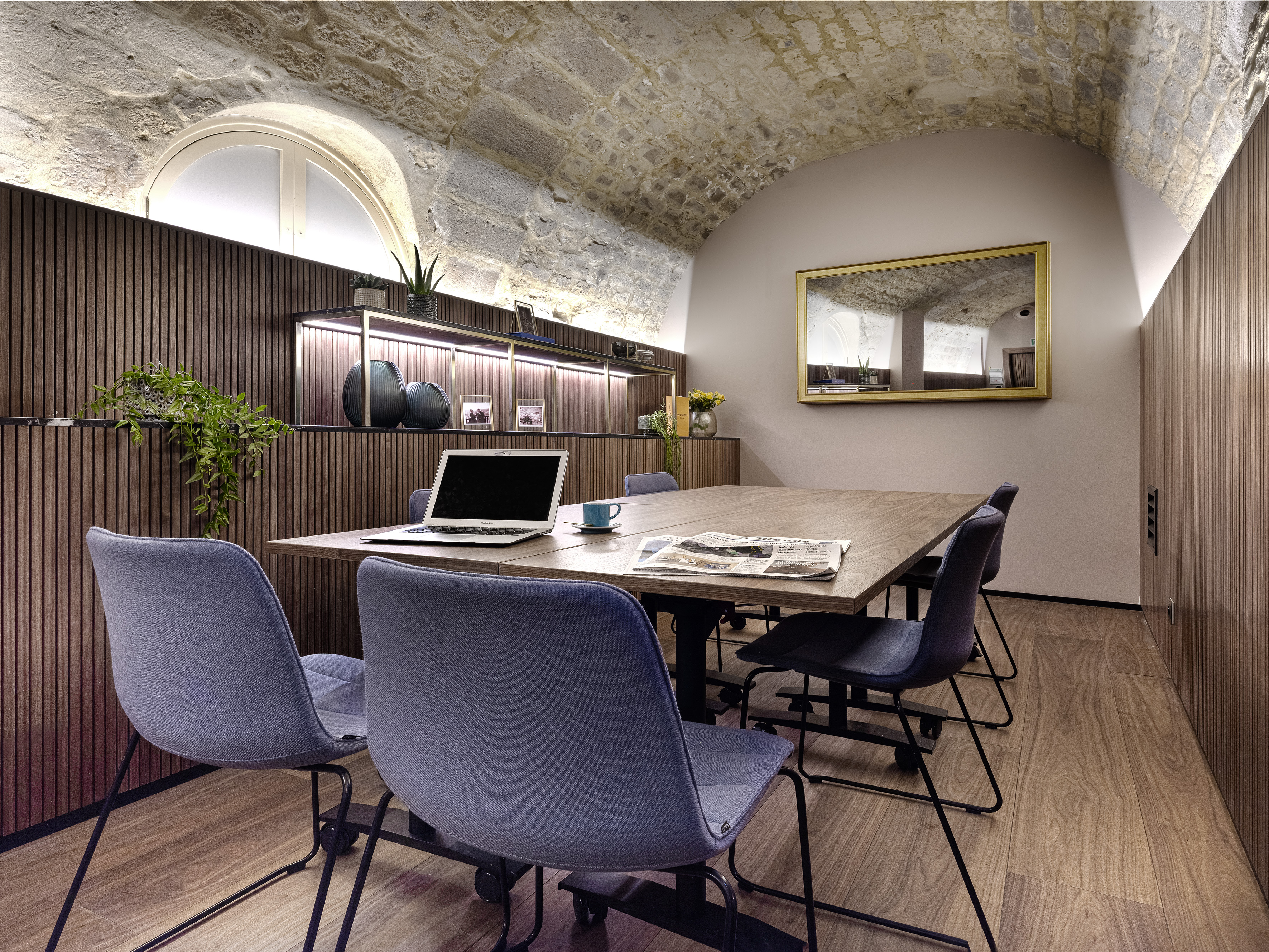 Conference room with vaulted stone ceiling, wood panels, modern office chairs.