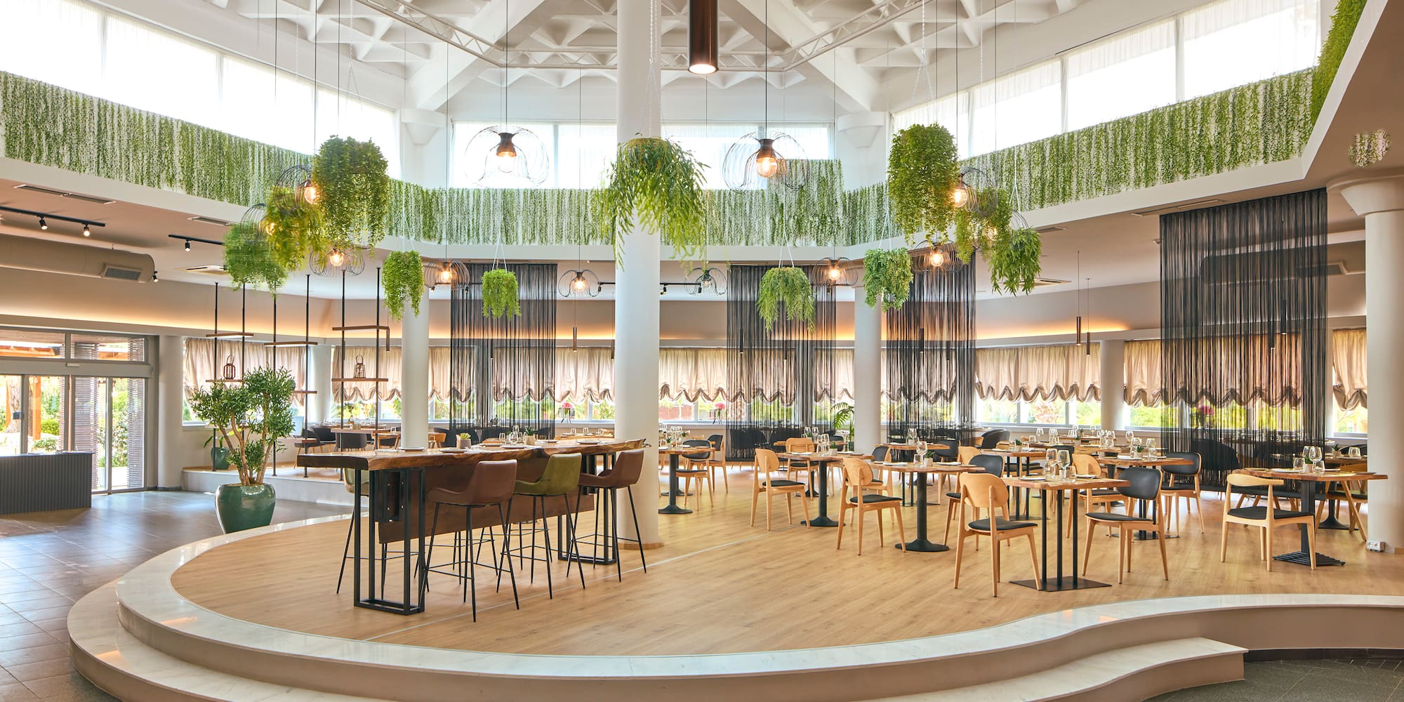 a room with tables and chairs and plants from the ceiling