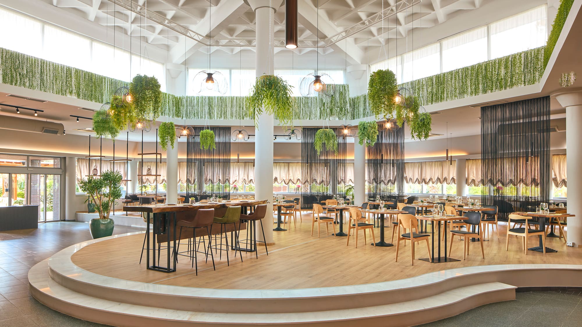 a room with tables and chairs and plants from the ceiling