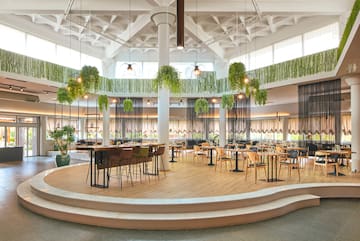 a room with tables and chairs and plants from the ceiling