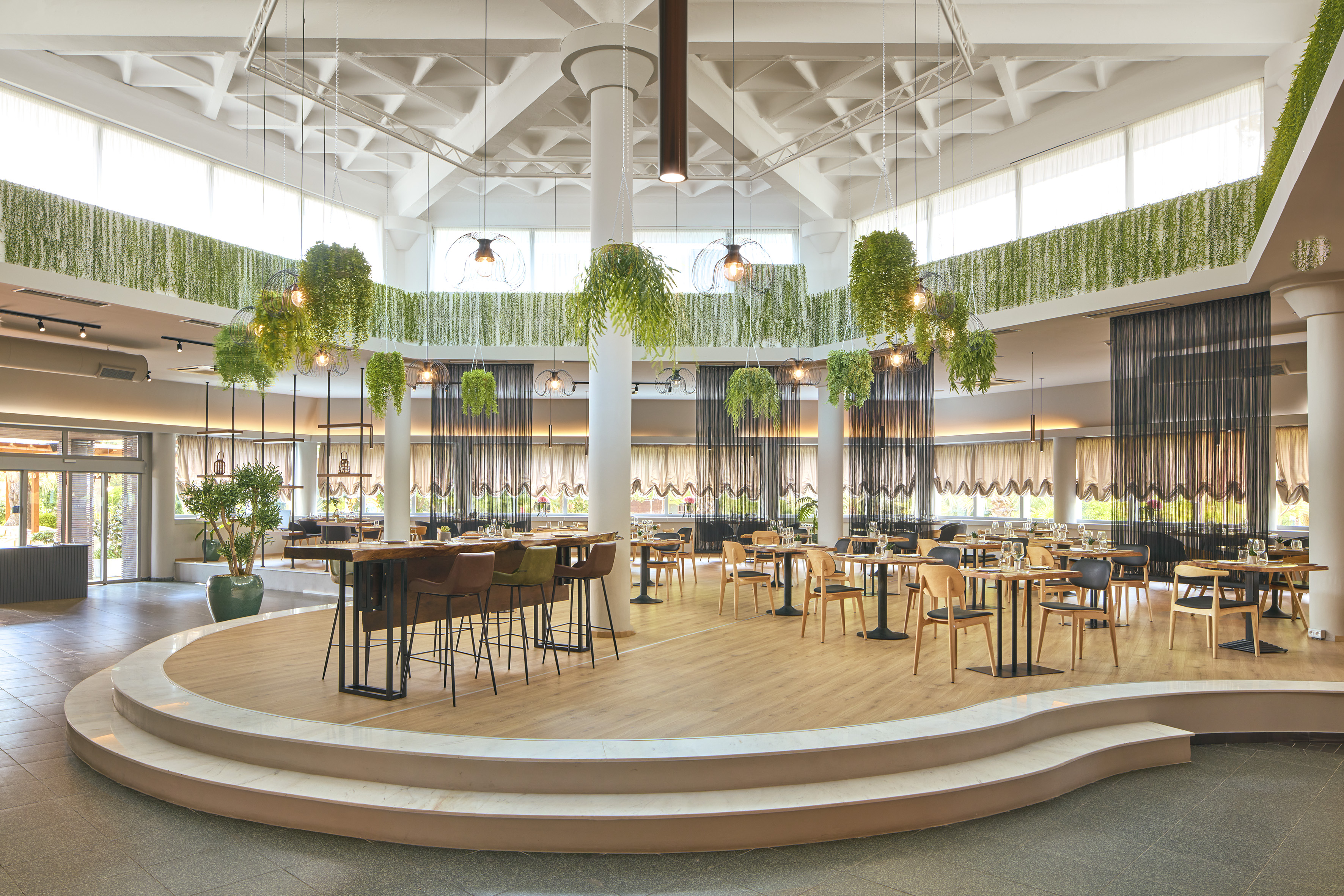 Spacious contemporary restaurant with hanging plants and diverse dining tables.