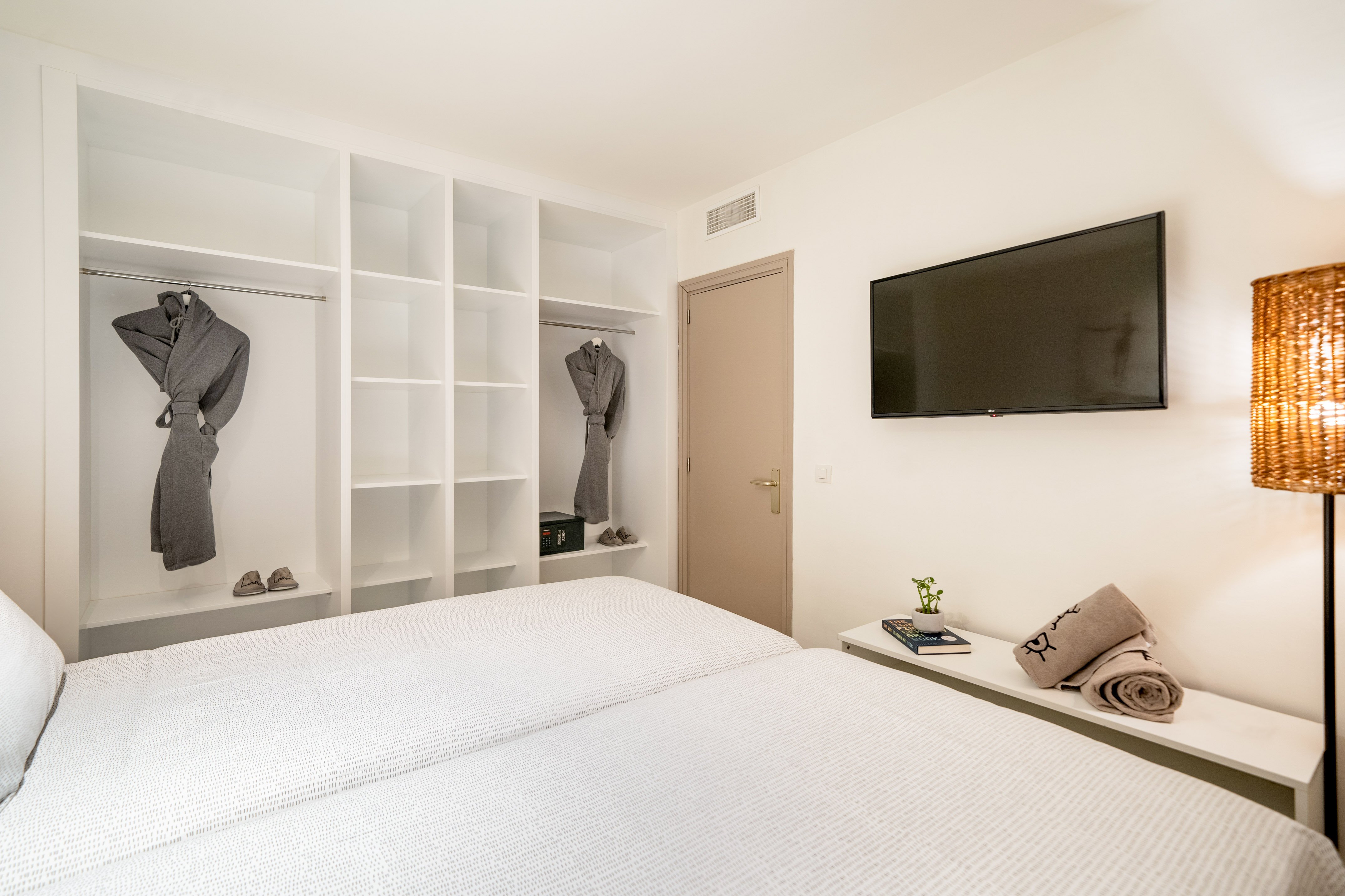 Modern twin bedroom with built-in wardrobe, TV, and hotel amenities.