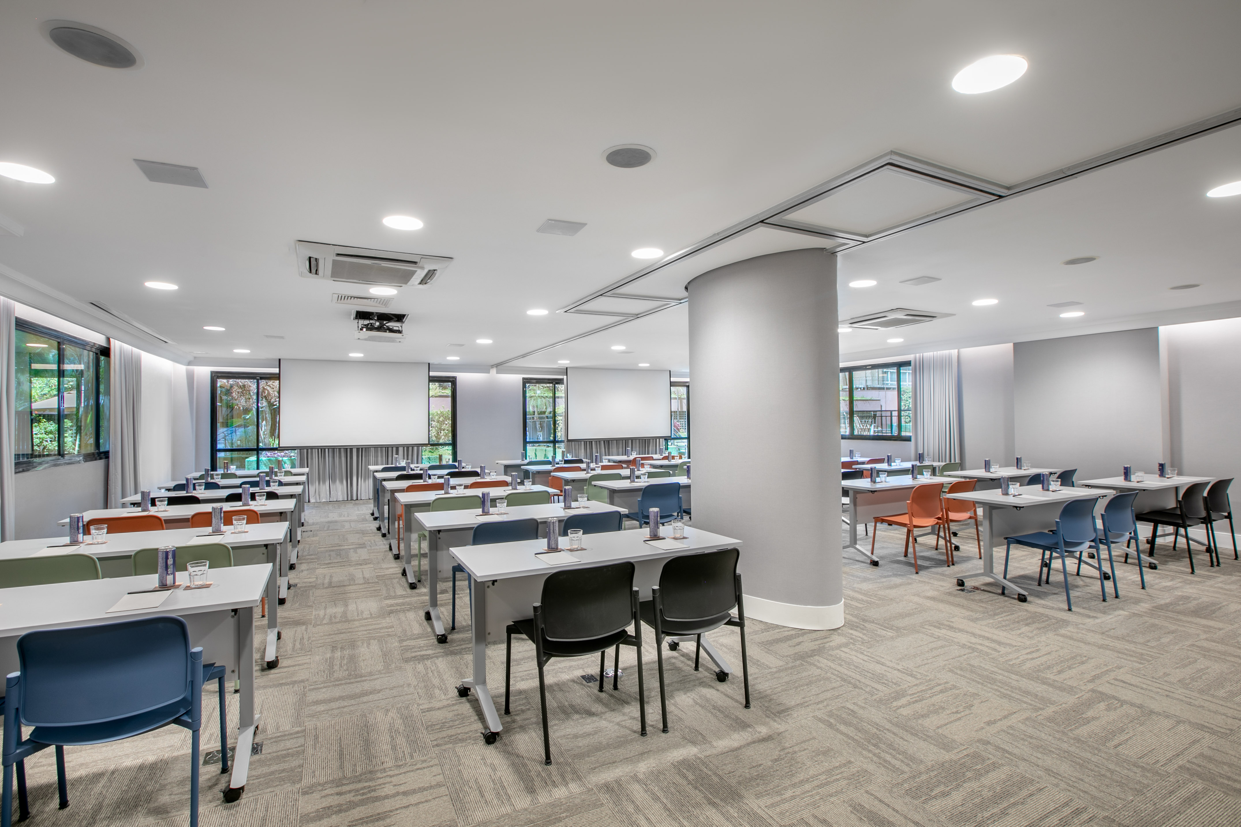 Empty modern conference room with colorful chairs, tables, and projection screens.