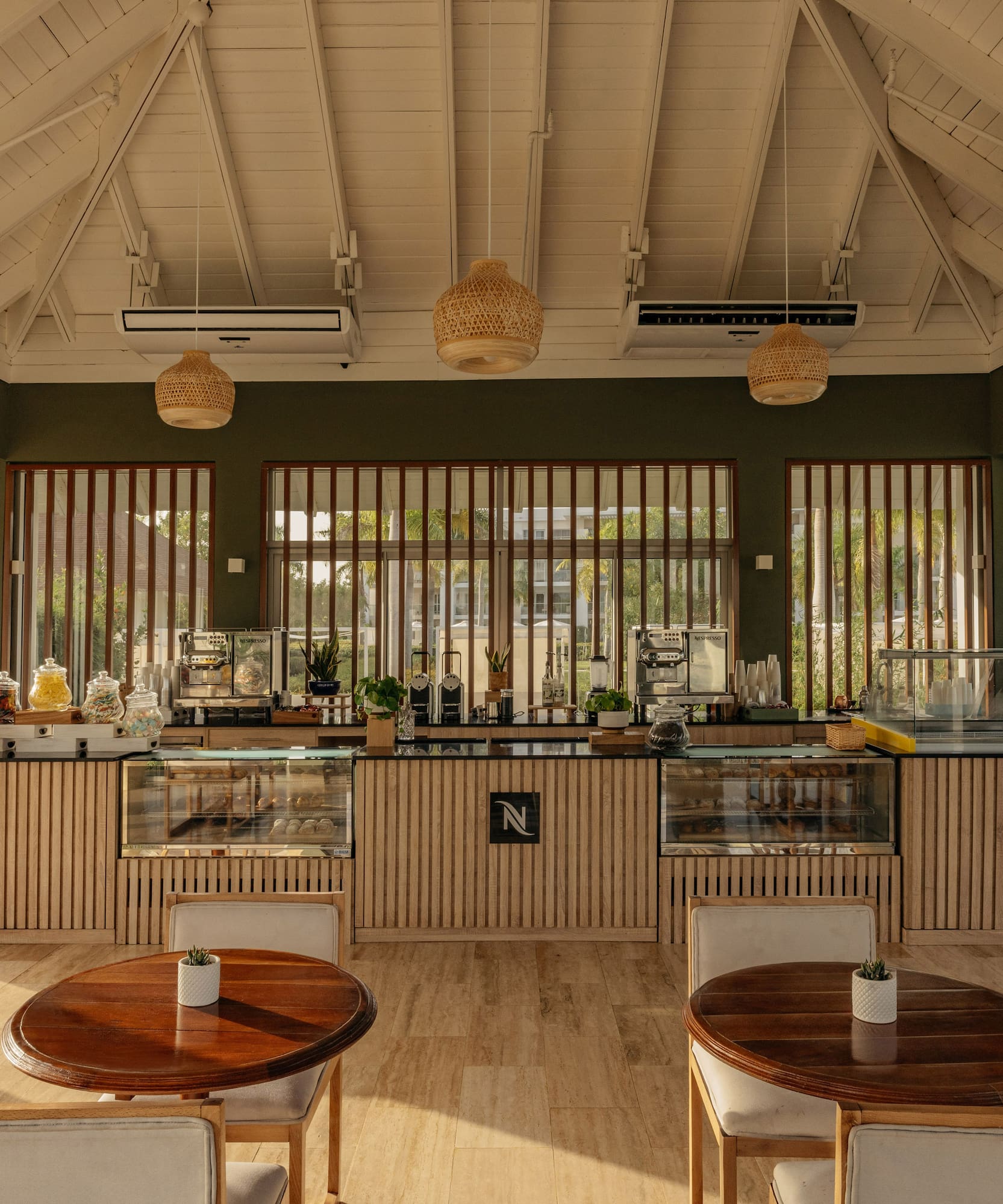 Modern resort cafe interior with Nespresso bar, wooden counter, and bright seating.