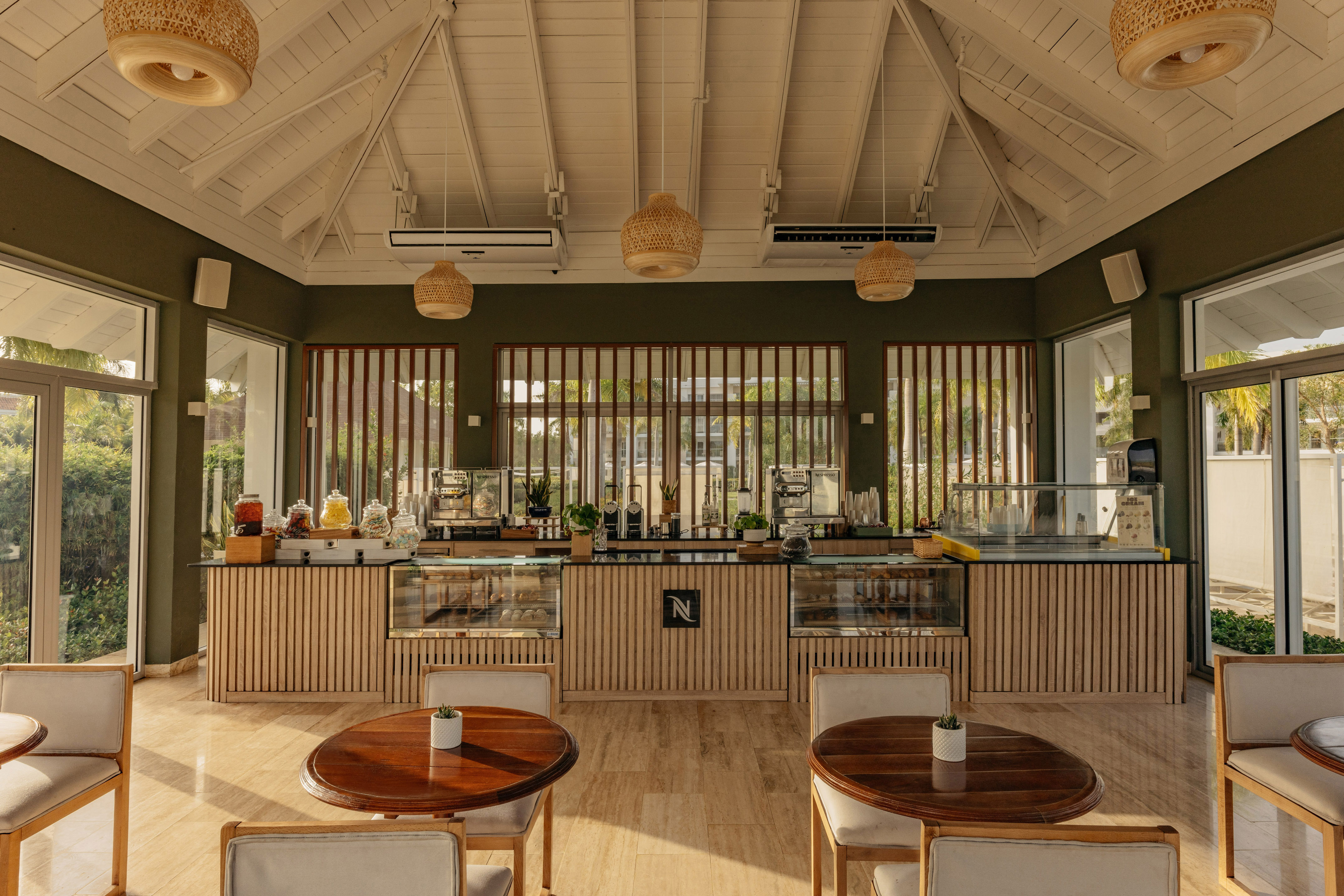 Modern resort cafe interior with Nespresso bar, wooden counter, and bright seating.
