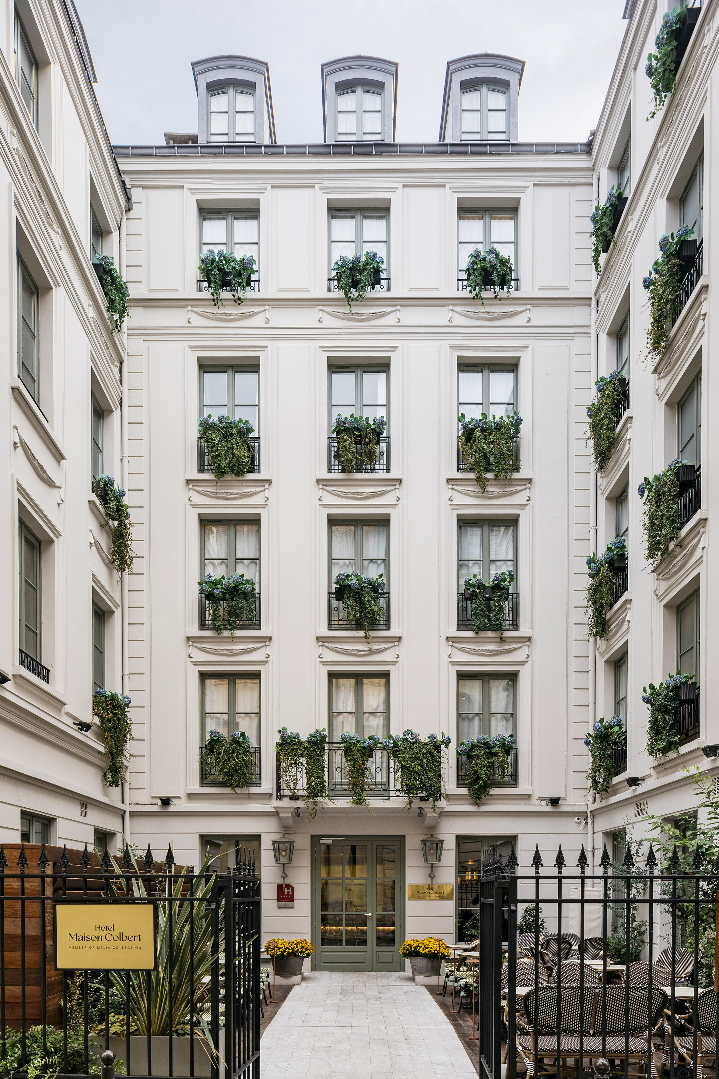 Maison Colbert hotel facade, Paris, green windows, overflowing flower boxes.