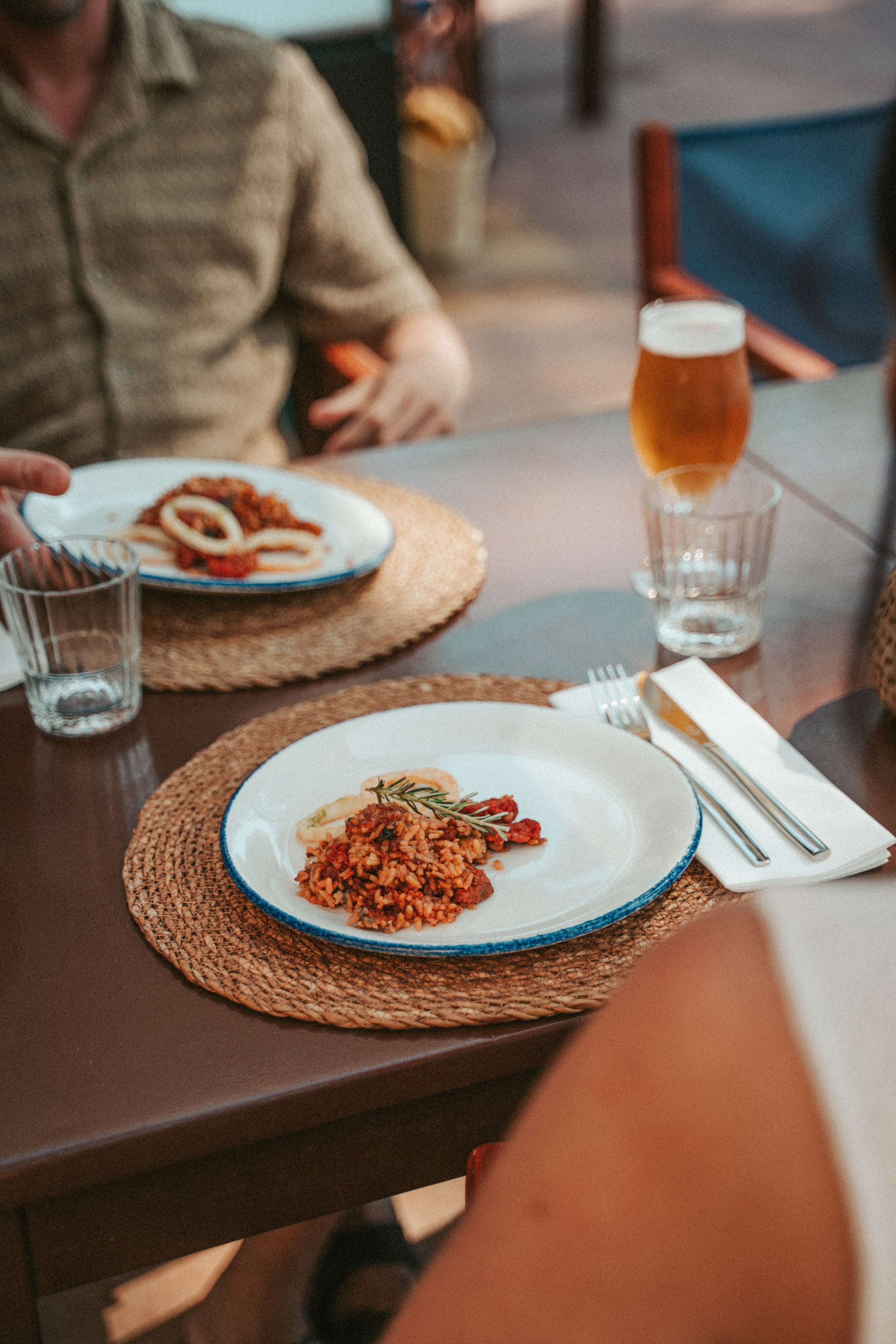 Rice dish, calamari, and beer on a table at a restaurant.