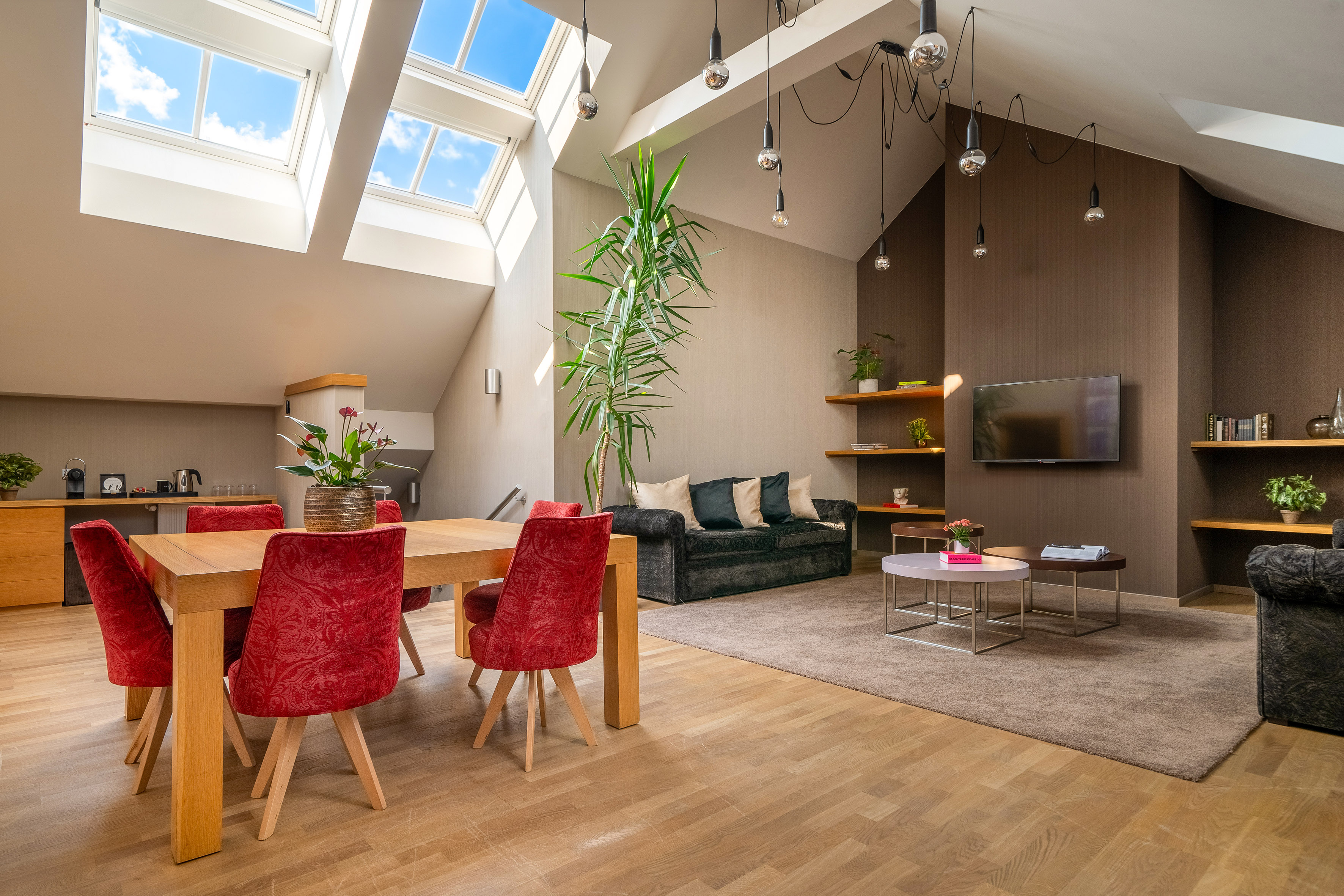 Modern loft living room with skylights, dining set, and contemporary decor.