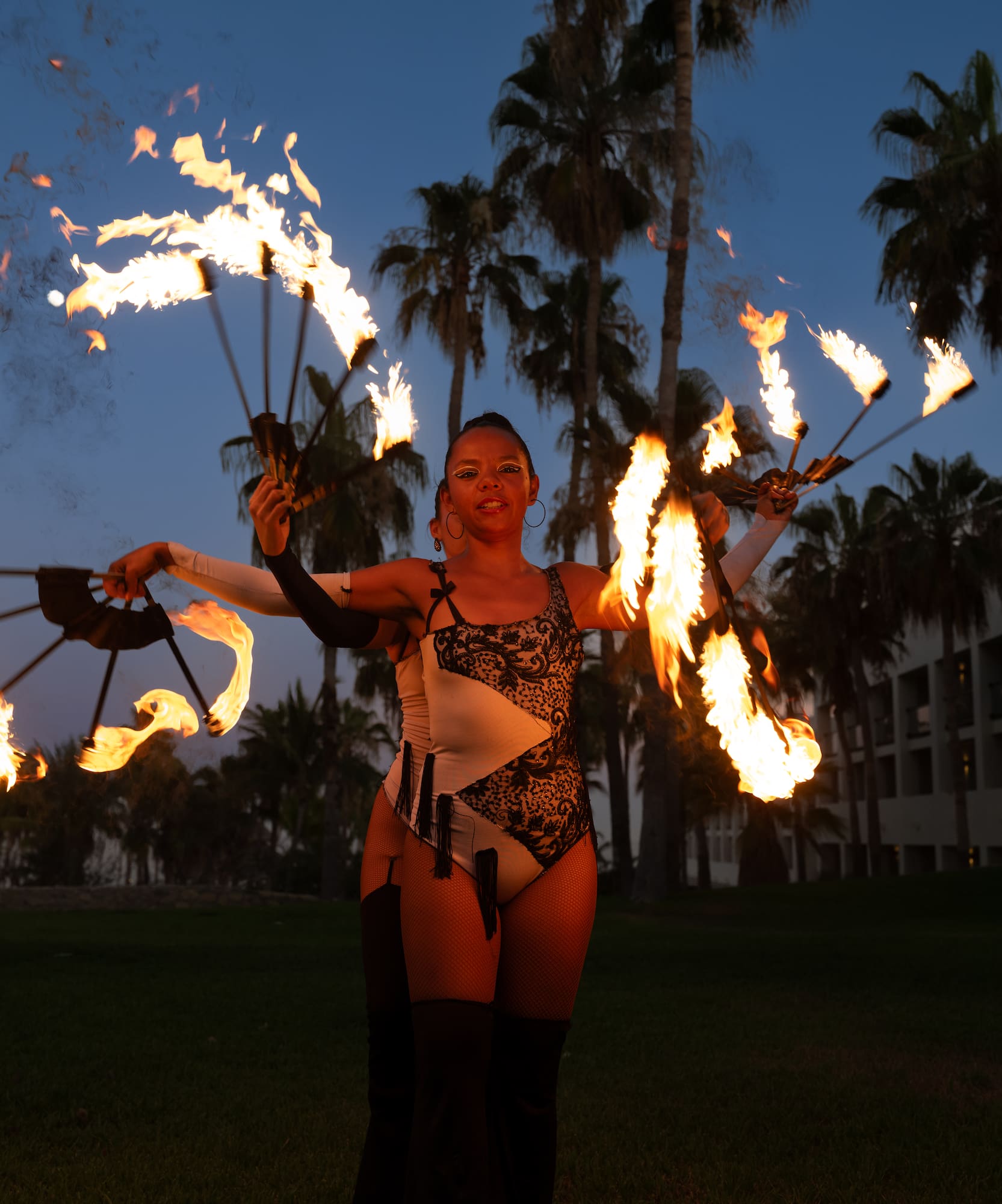 a woman with fire juggling with palm trees