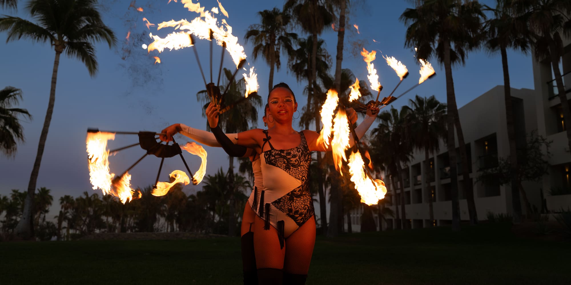 a woman with fire juggling with palm trees