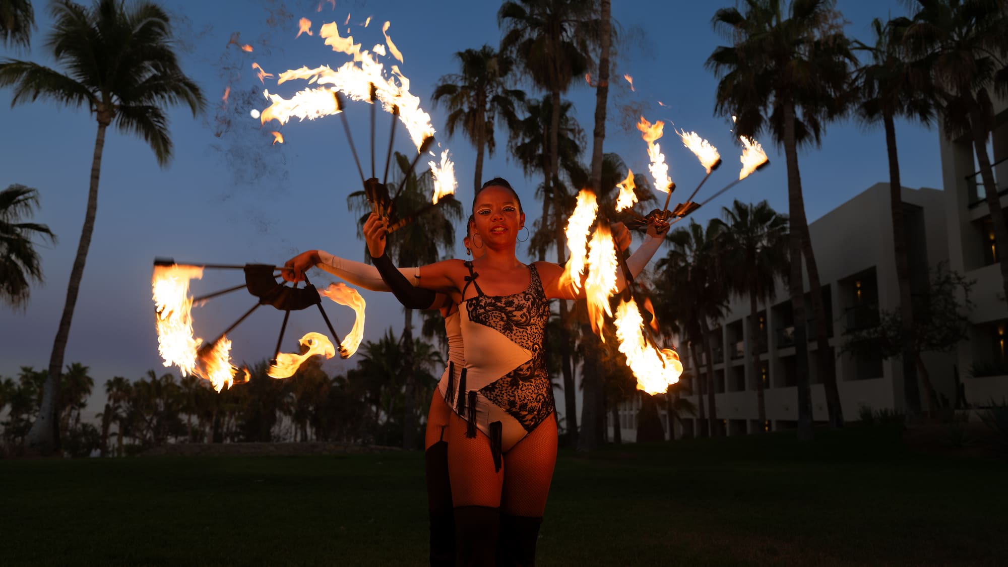 a woman with fire juggling with palm trees