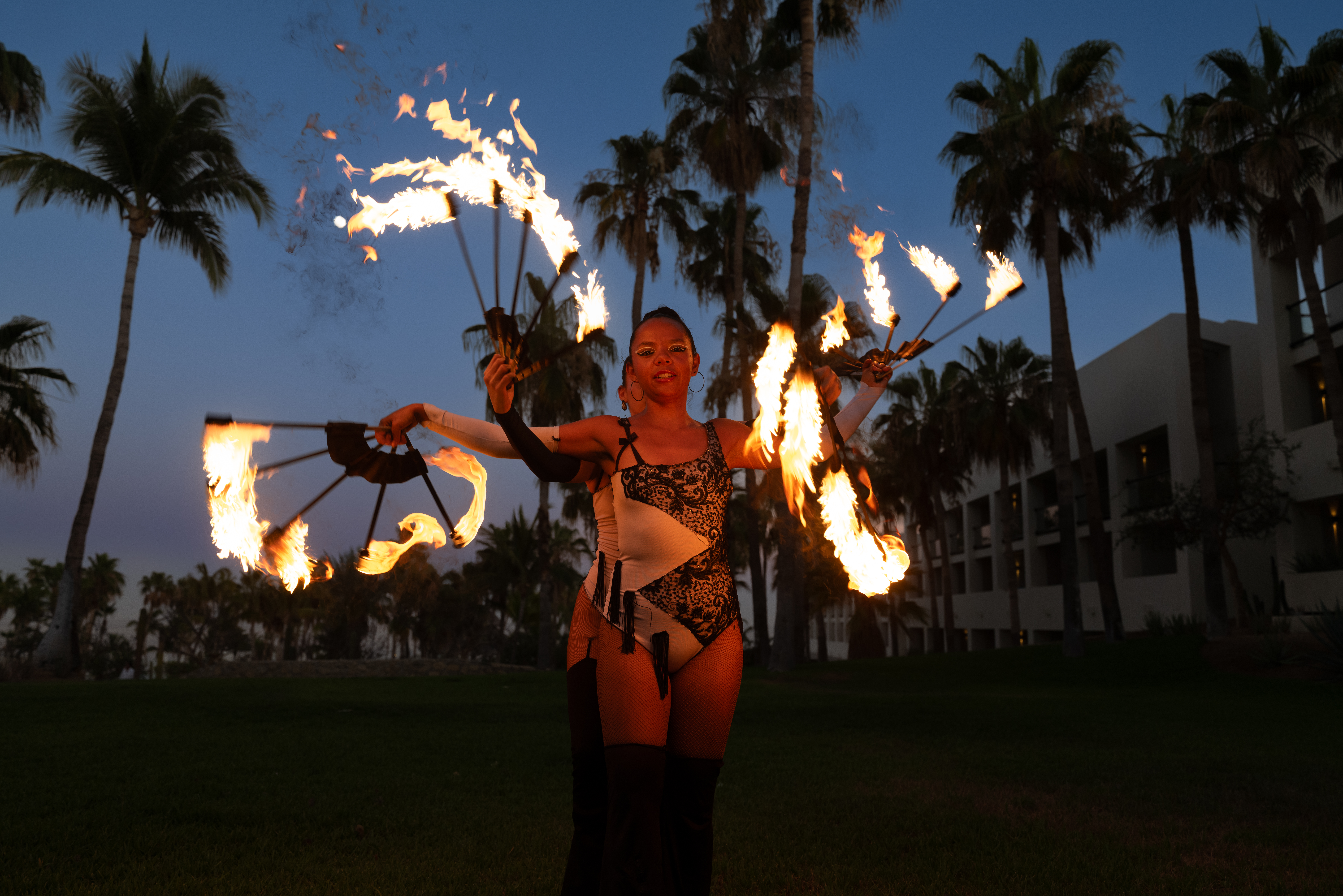 a woman with fire juggling with palm trees