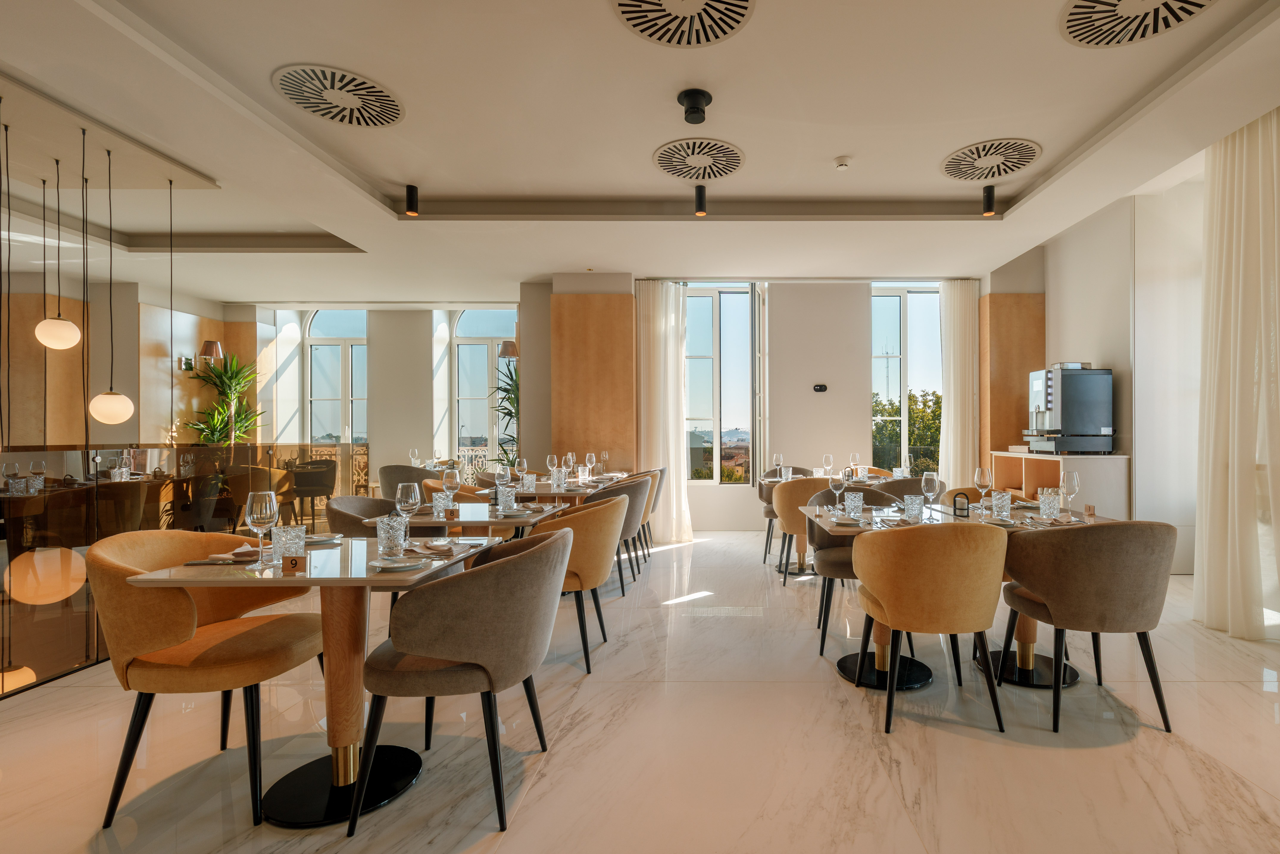 Elegant hotel restaurant with set tables, contemporary chairs, and large windows.