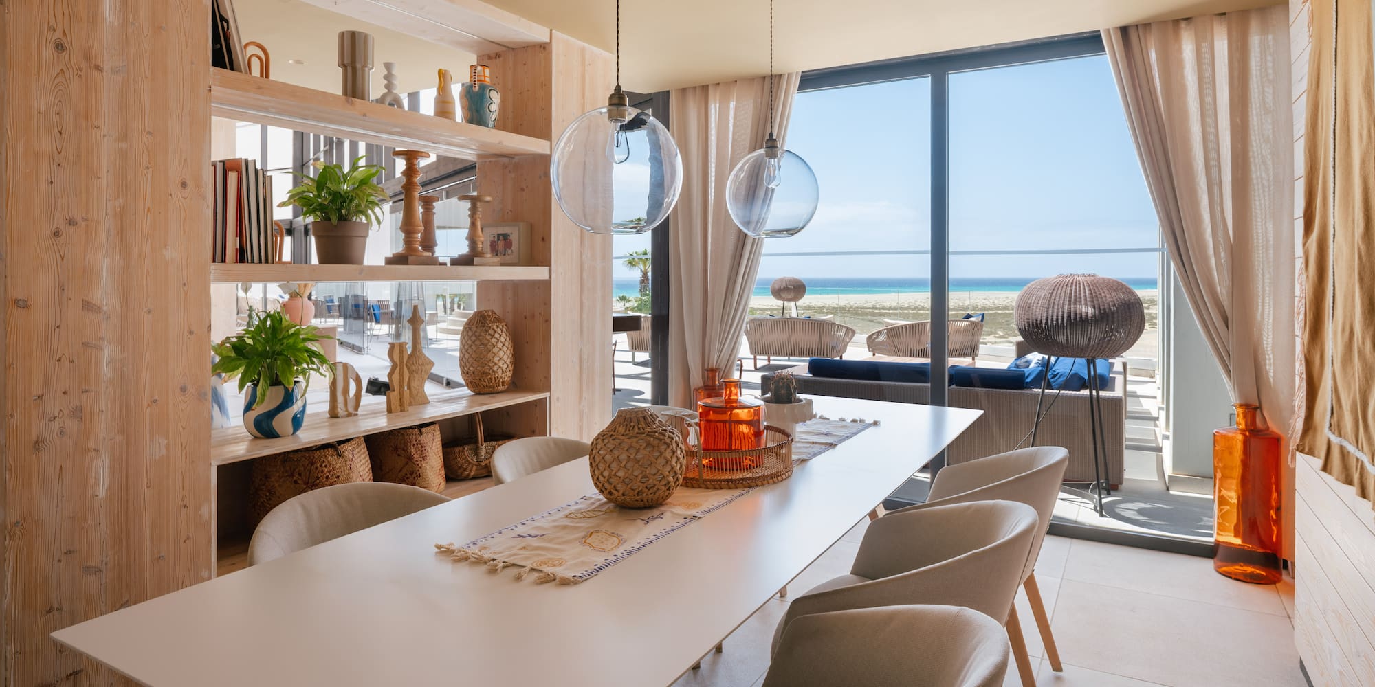 Beachfront dining room with ocean view, long table, and modern decor.
