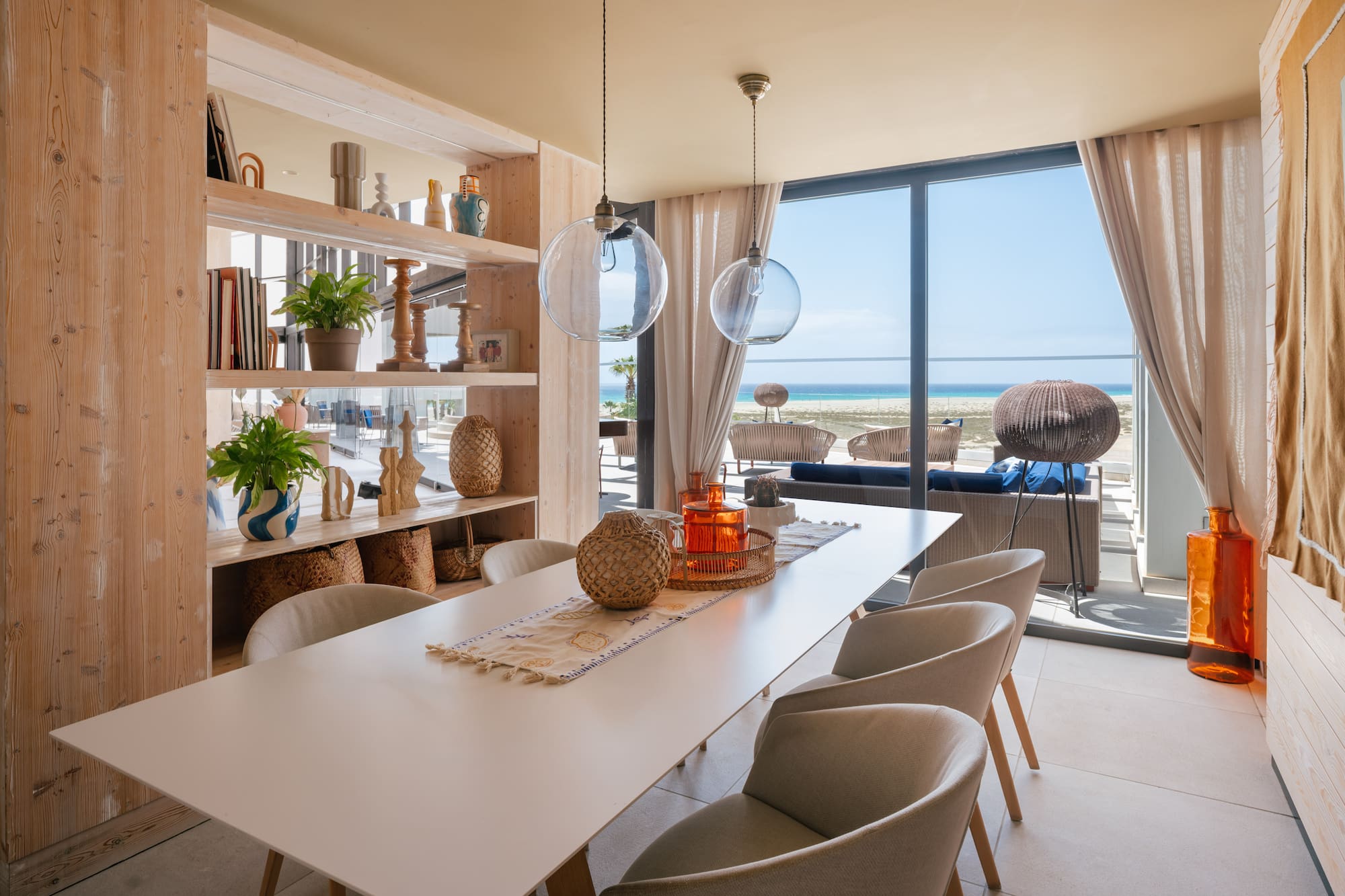 Beachfront dining room with ocean view, long table, and modern decor.