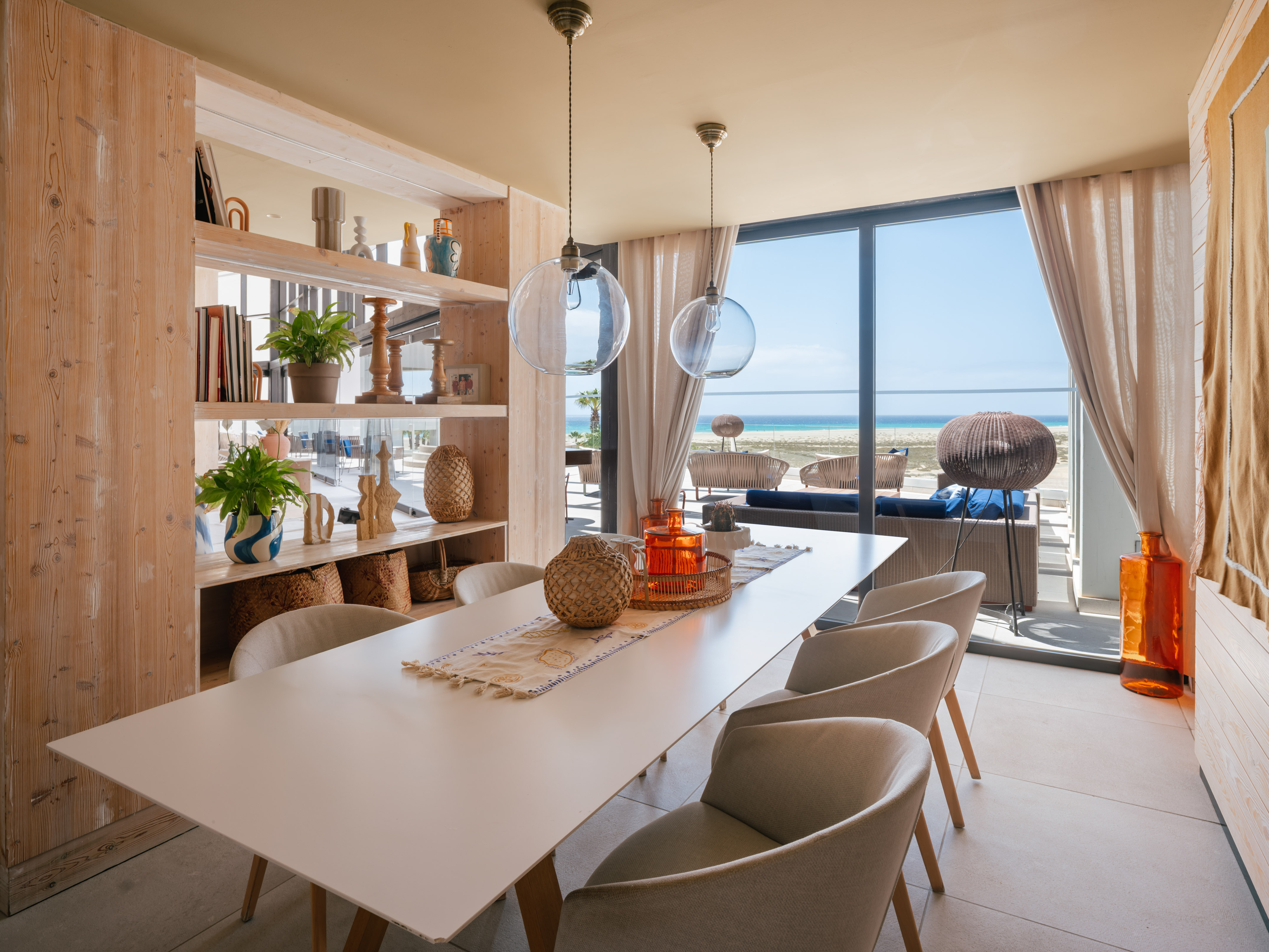 Beachfront dining room with ocean view, long table, and modern decor.