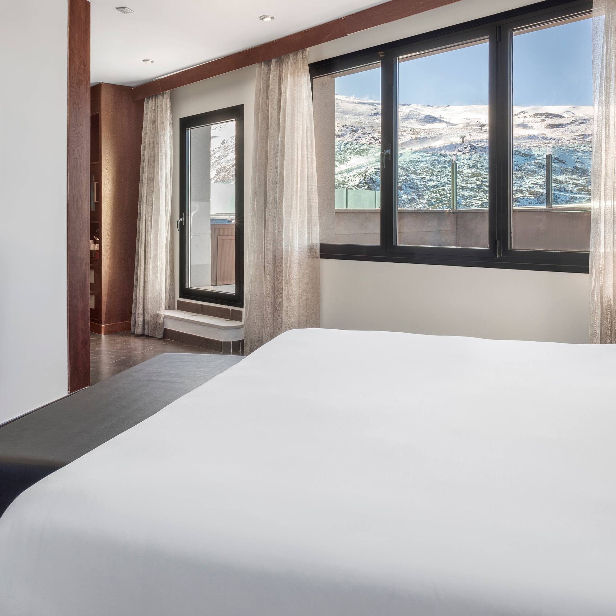 a bed in a room with a window and a view of the mountains