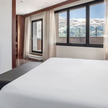 a bed in a room with a window and a view of the mountains