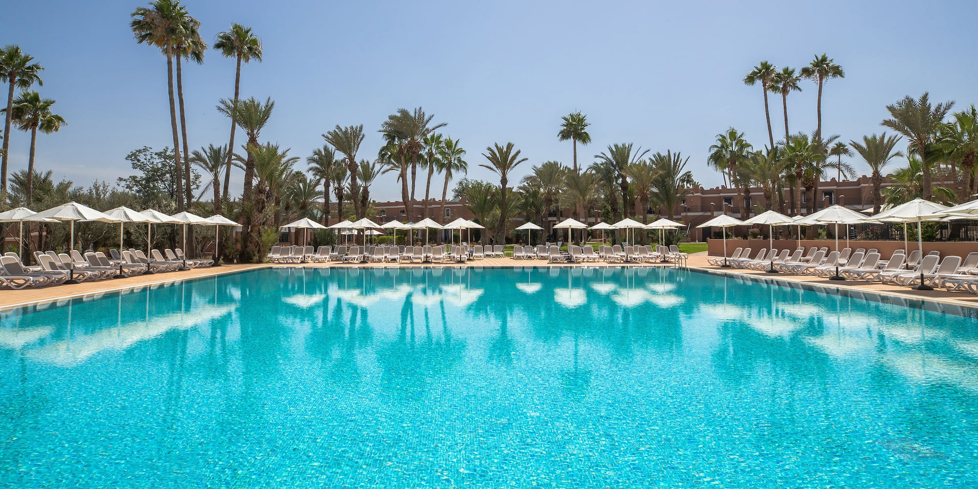 a pool with white umbrellas and palm trees