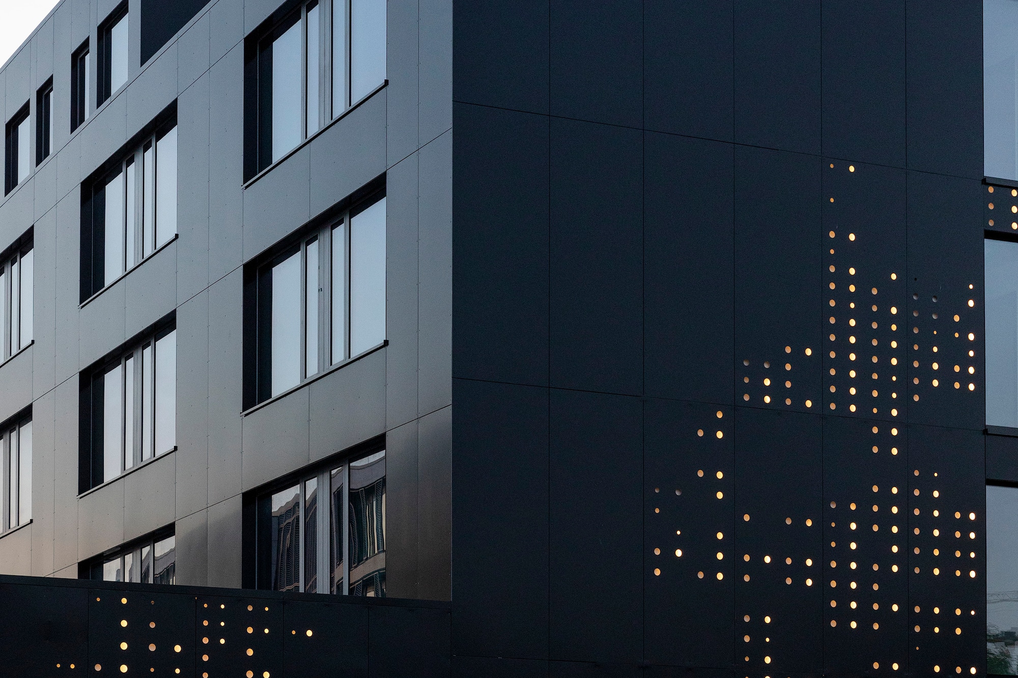 Modern black INNSIDE hotel facade with white logo and illuminated dot pattern.