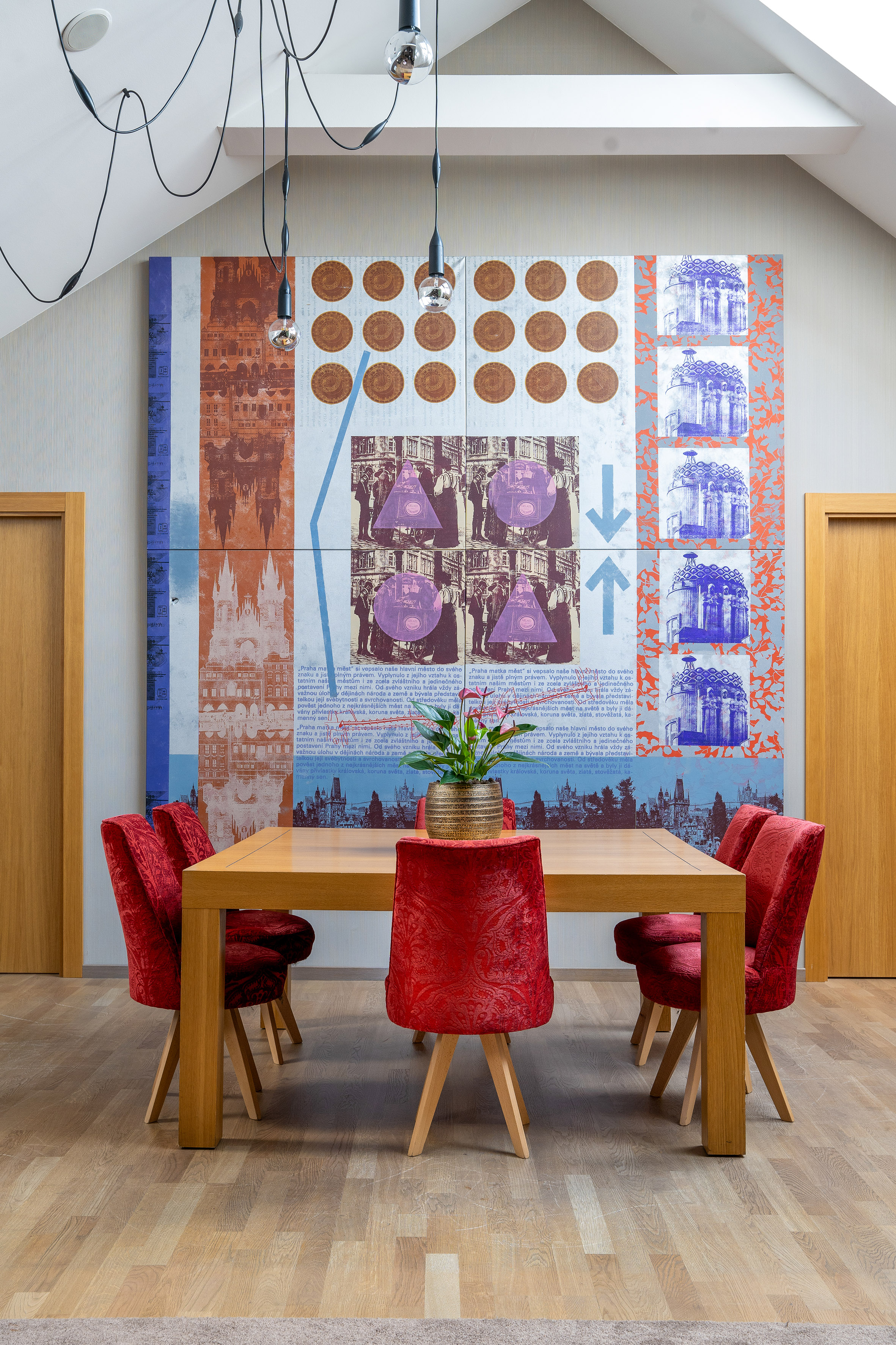 Modern dining room featuring pop art Prague mural, wood table, and red chairs.