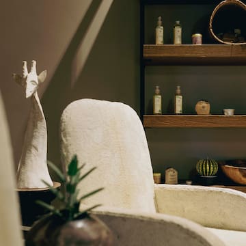 a white chair with a vase on a table with a plant on it