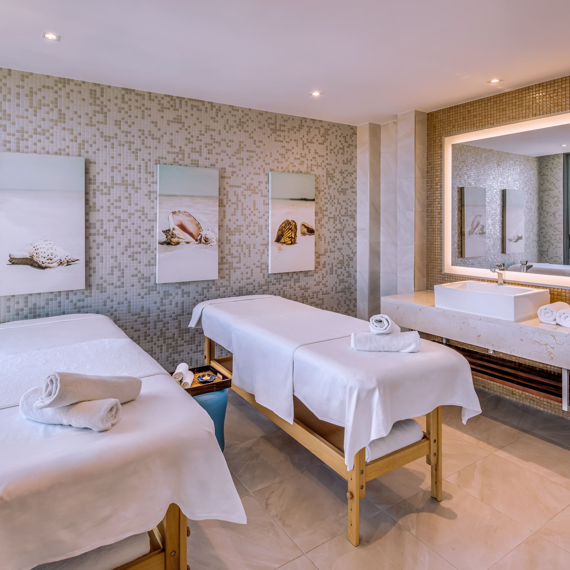 a massage room with two beds and a sink