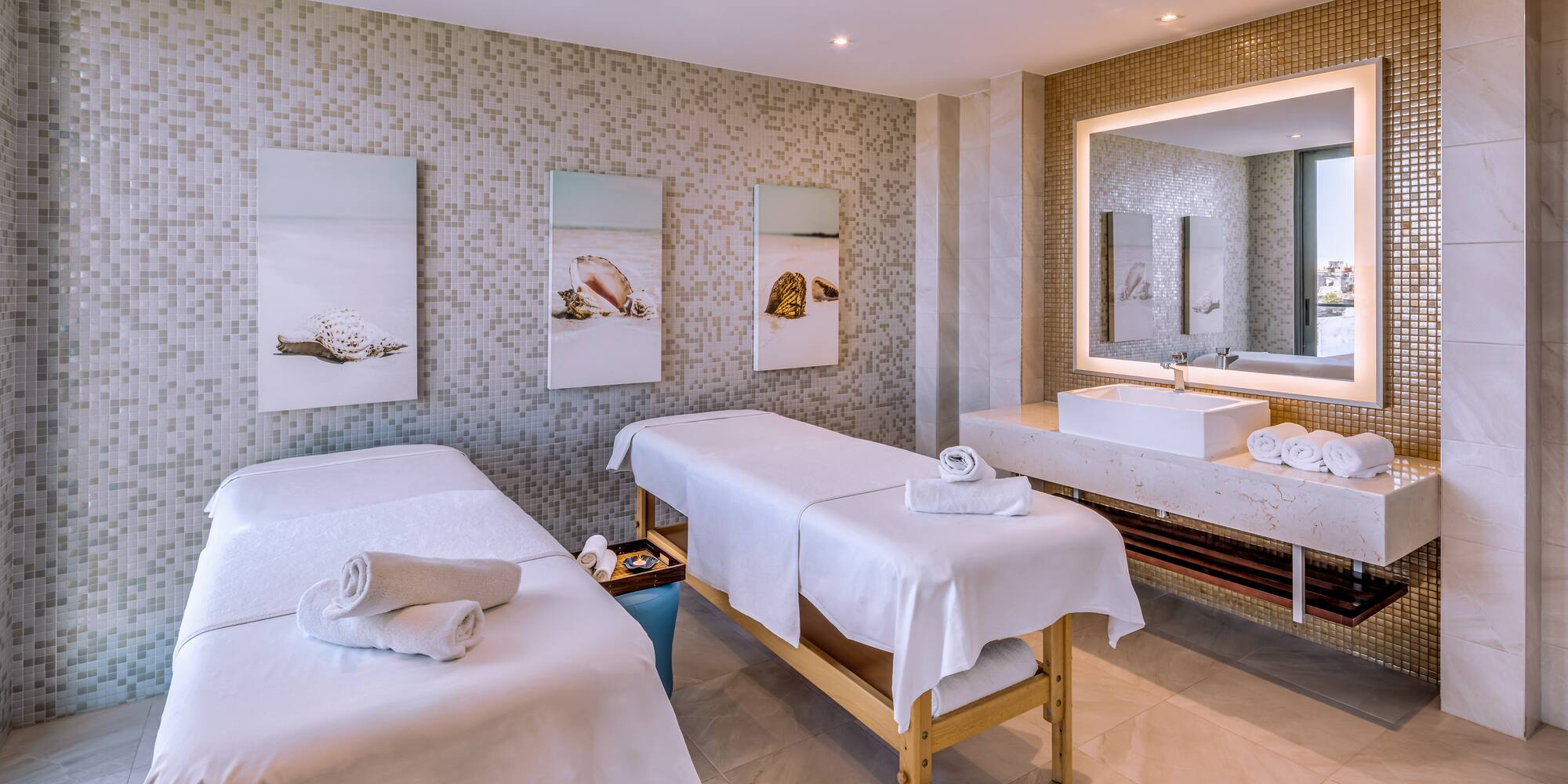 a massage room with two beds and a sink