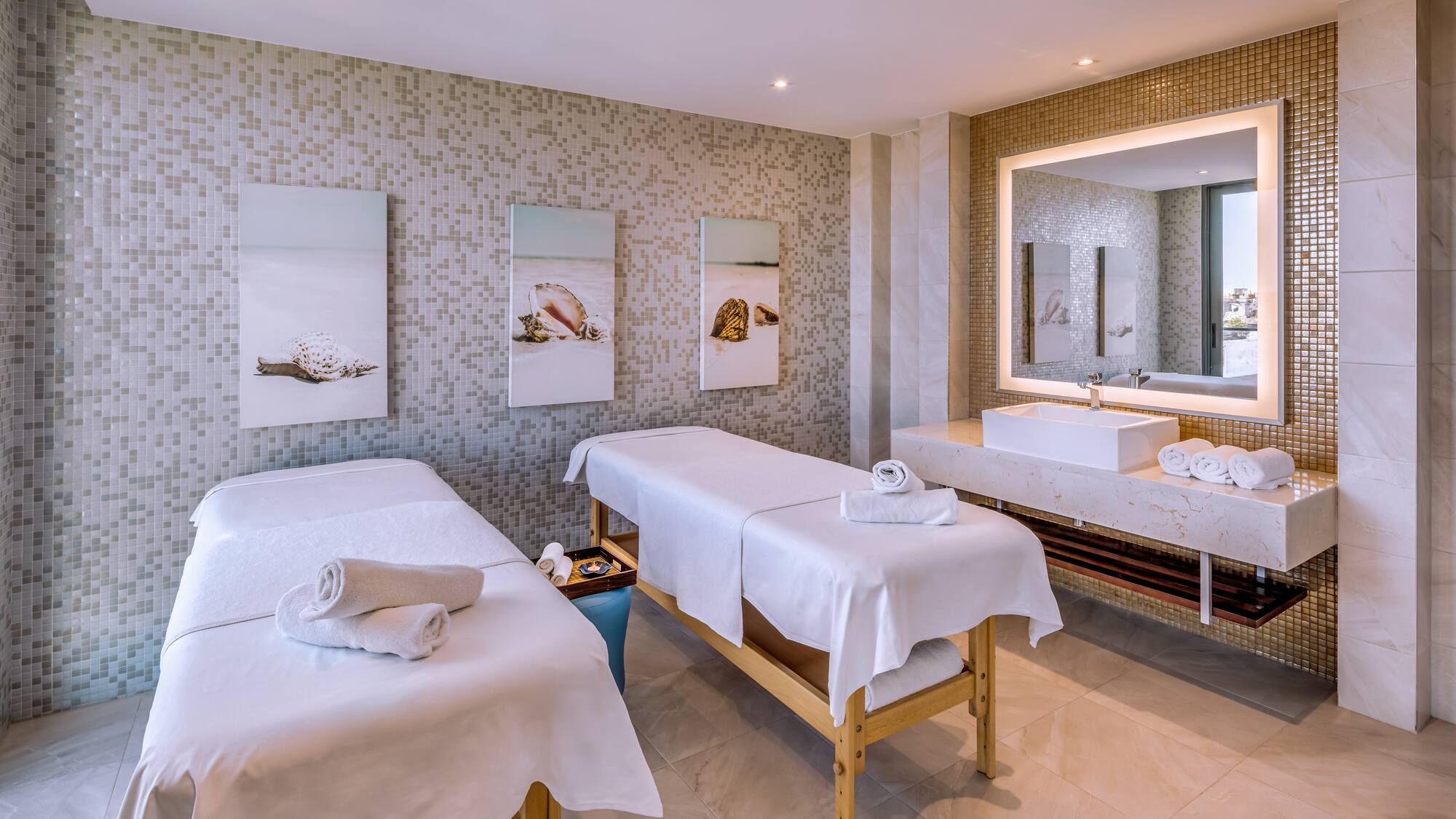 a massage room with two beds and a sink