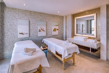 a massage room with two beds and a sink