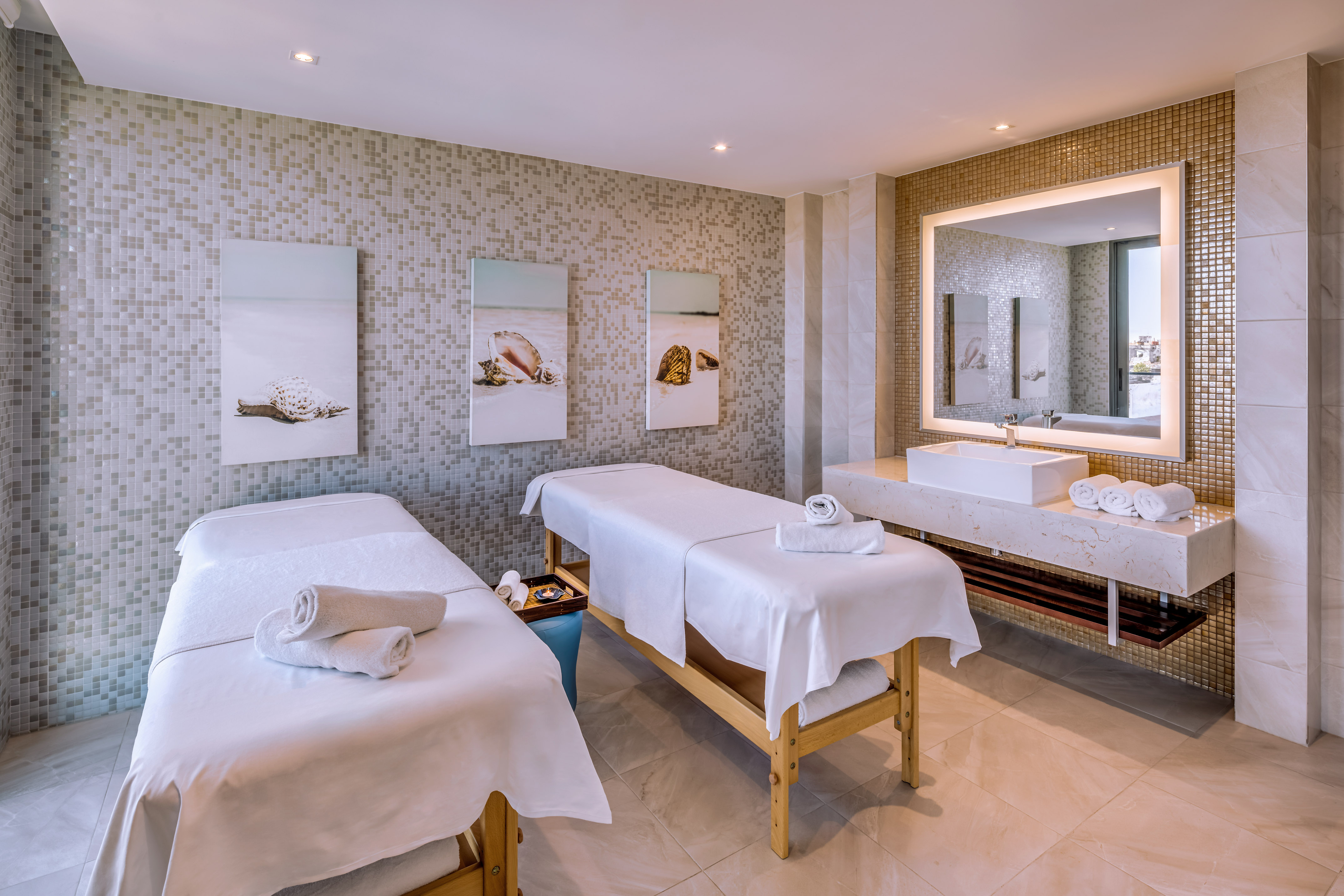 a massage room with two beds and a sink