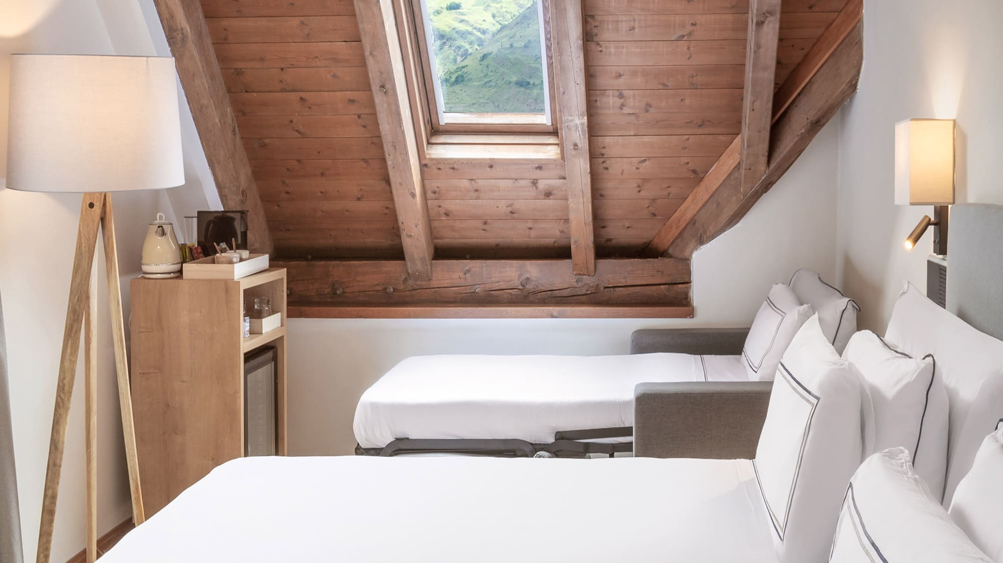 a room with white beds and a wooden ceiling