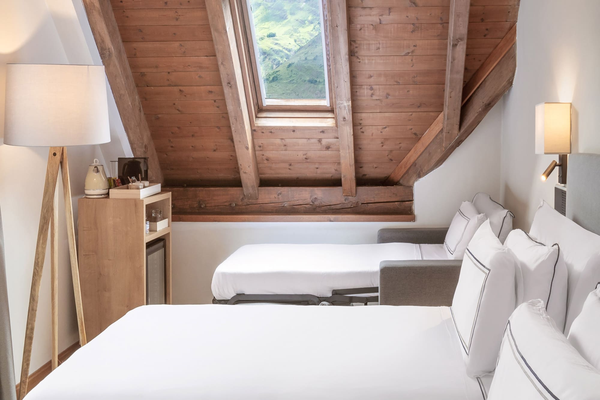 a room with white beds and a wooden ceiling