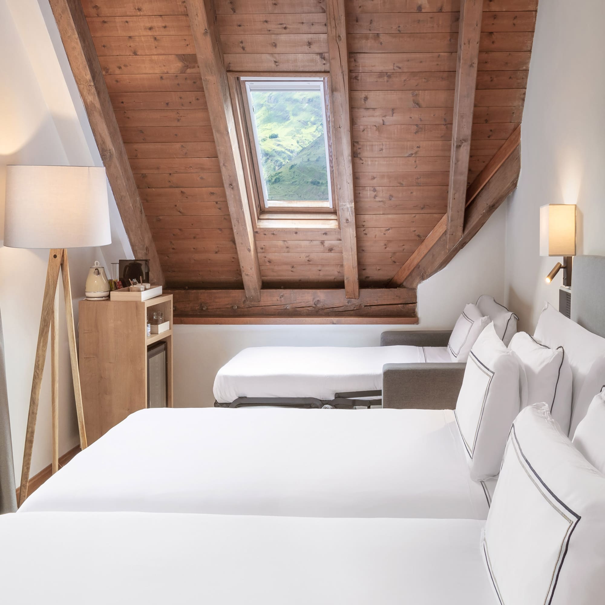 a room with white beds and a wooden ceiling