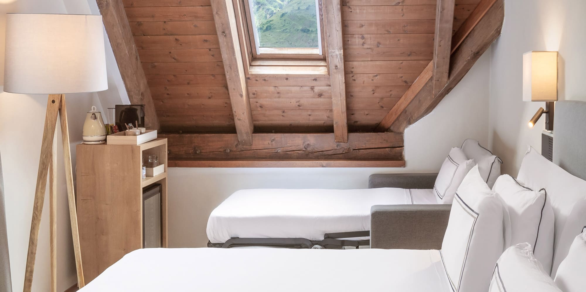 a room with white beds and a wooden ceiling