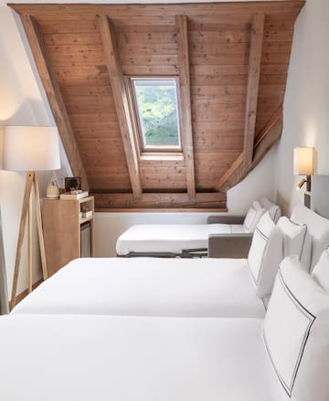 a room with white beds and a wooden ceiling