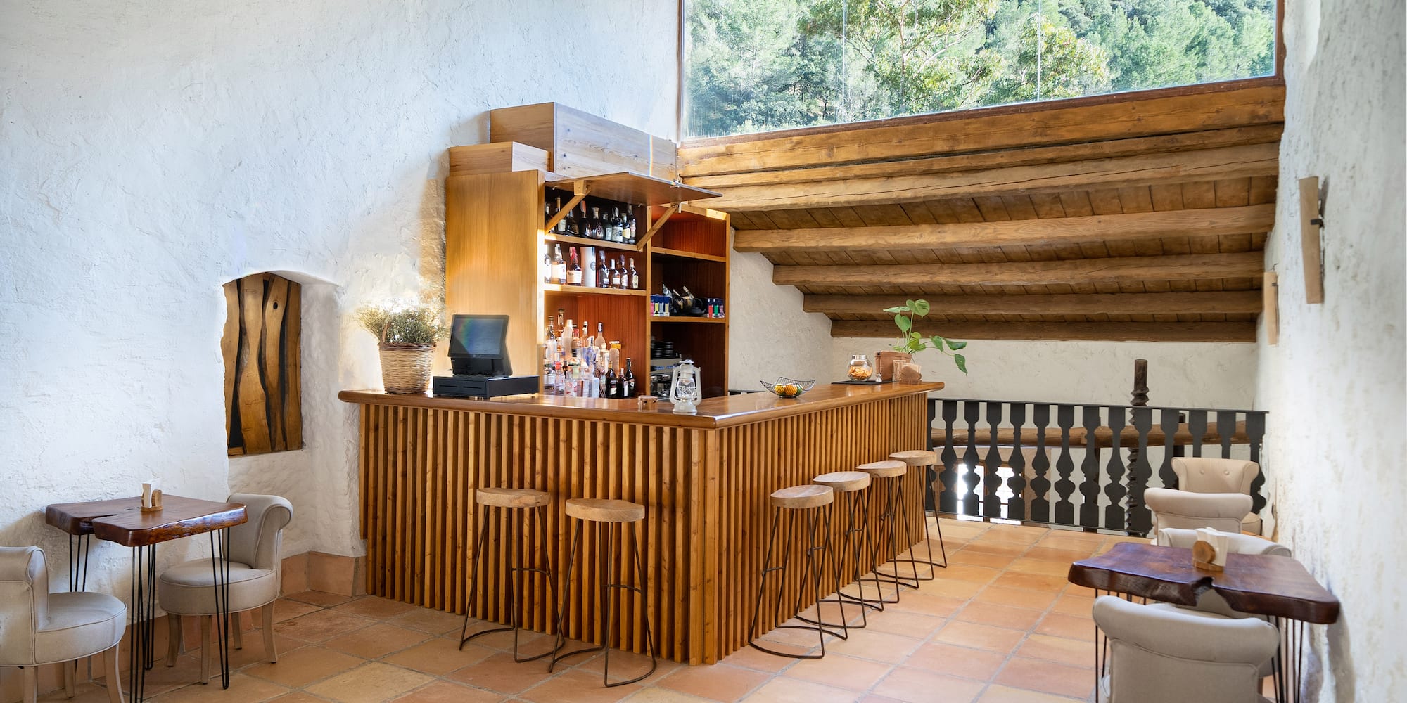 a bar in a room with a roof and chairs