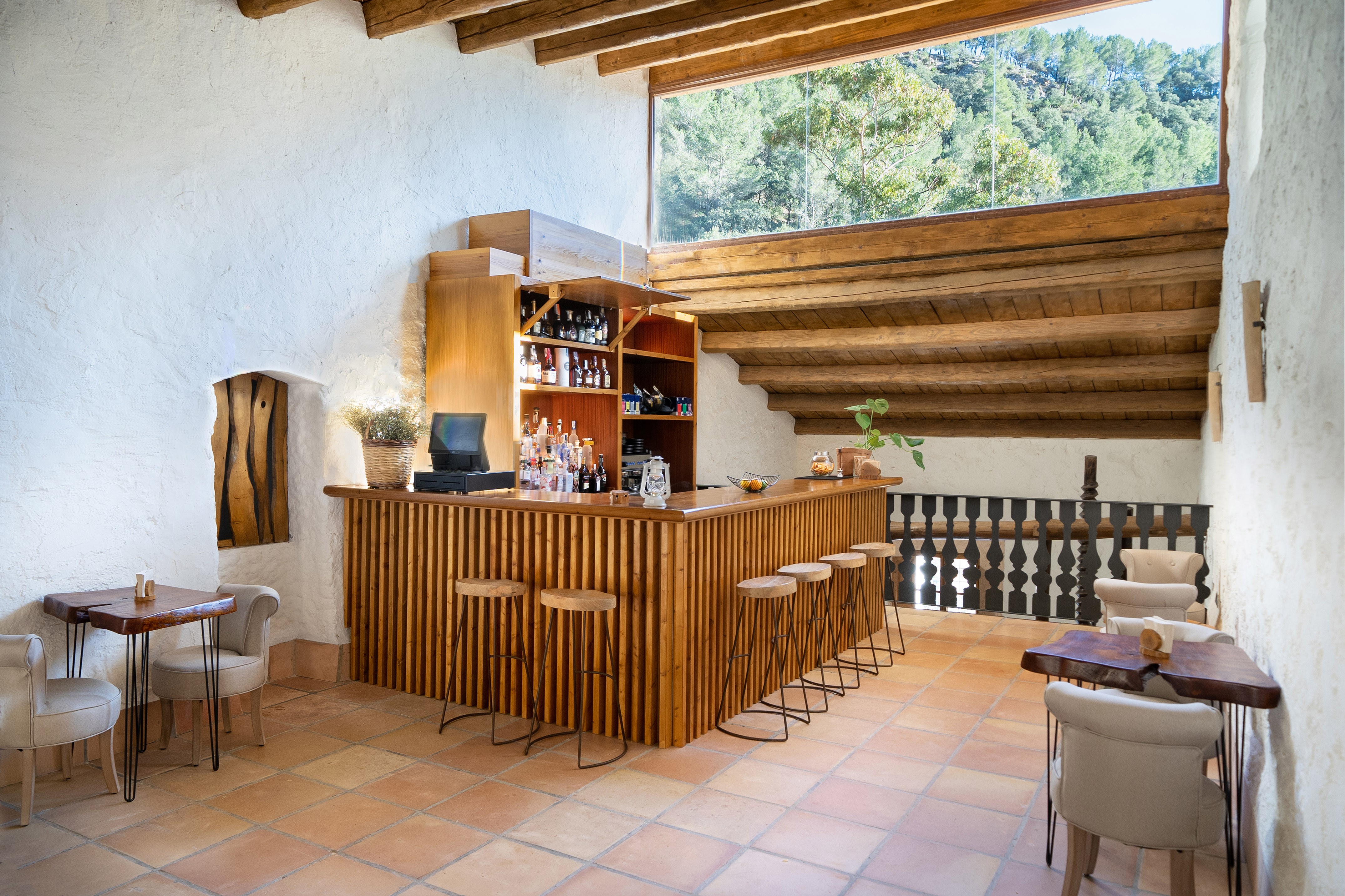 Rustic wooden bar, exposed beams, terracotta floor, lounge seating, nature view.