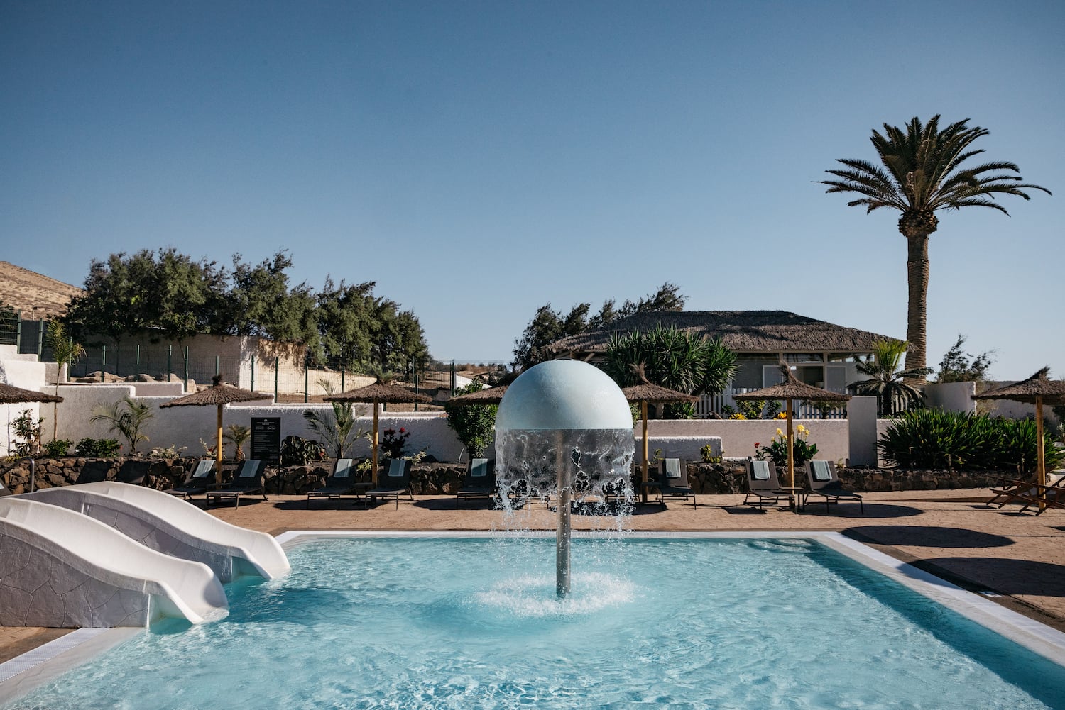 a pool with a water slide and a white ball