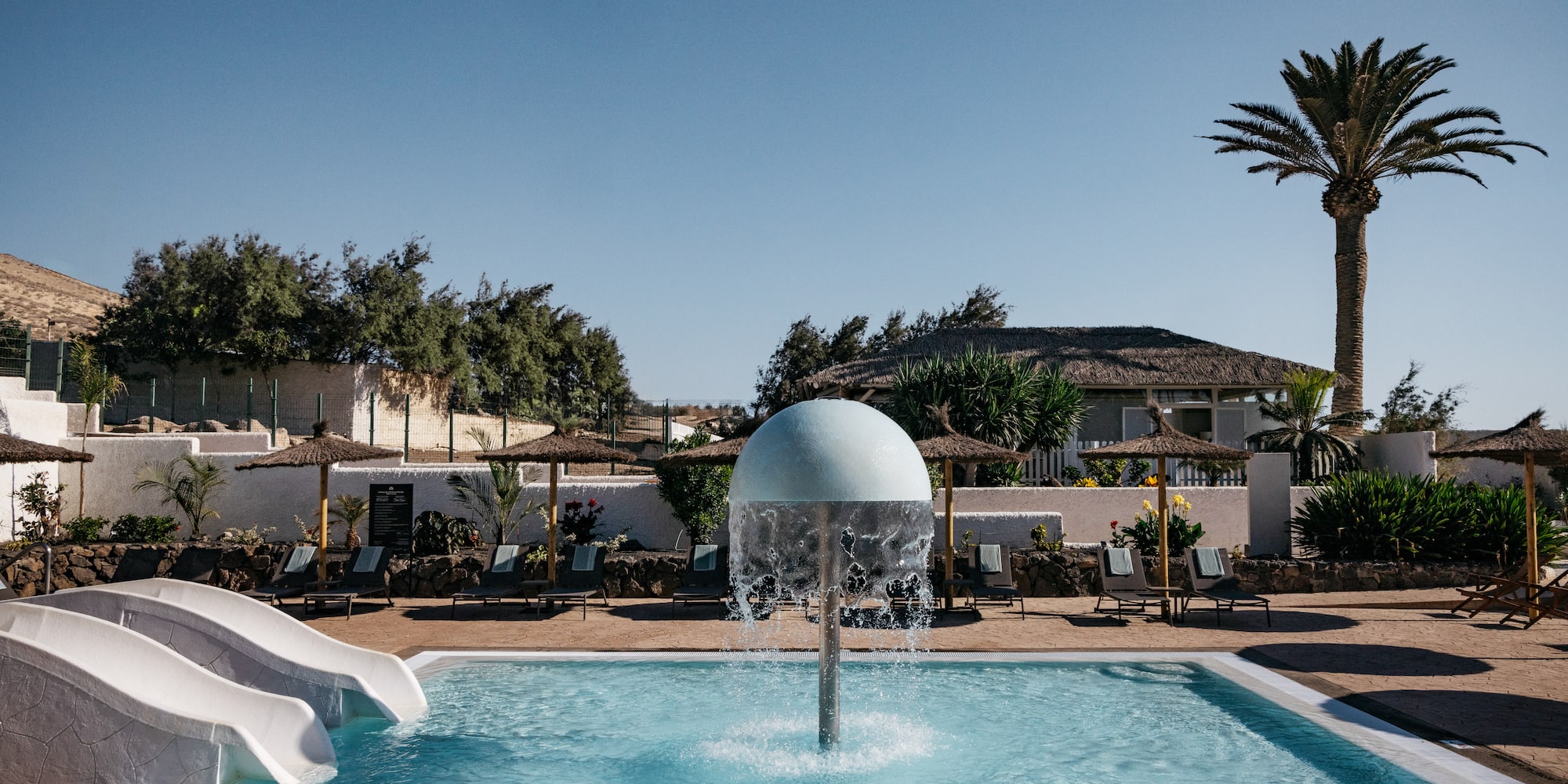a pool with a water slide and a white ball
