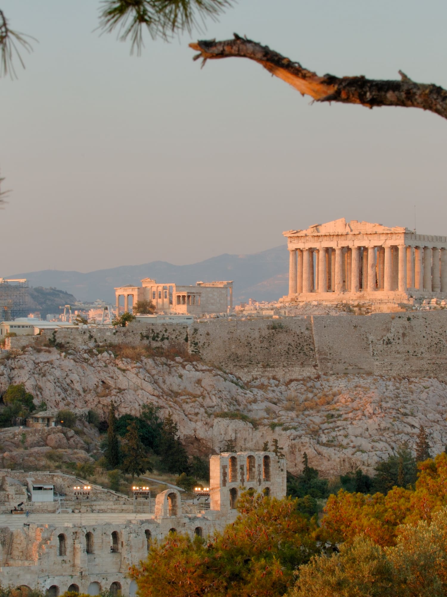 a stone buildings with columns and a hill with trees