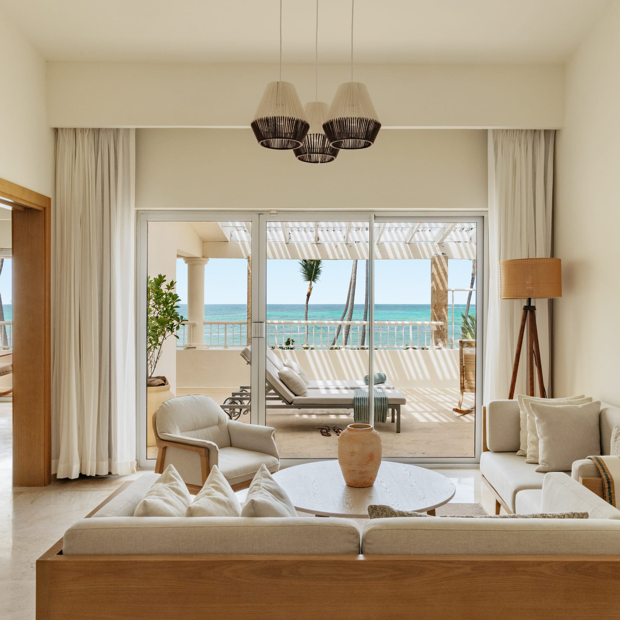 Luxury suite living room with ocean view balcony and tropical palms.