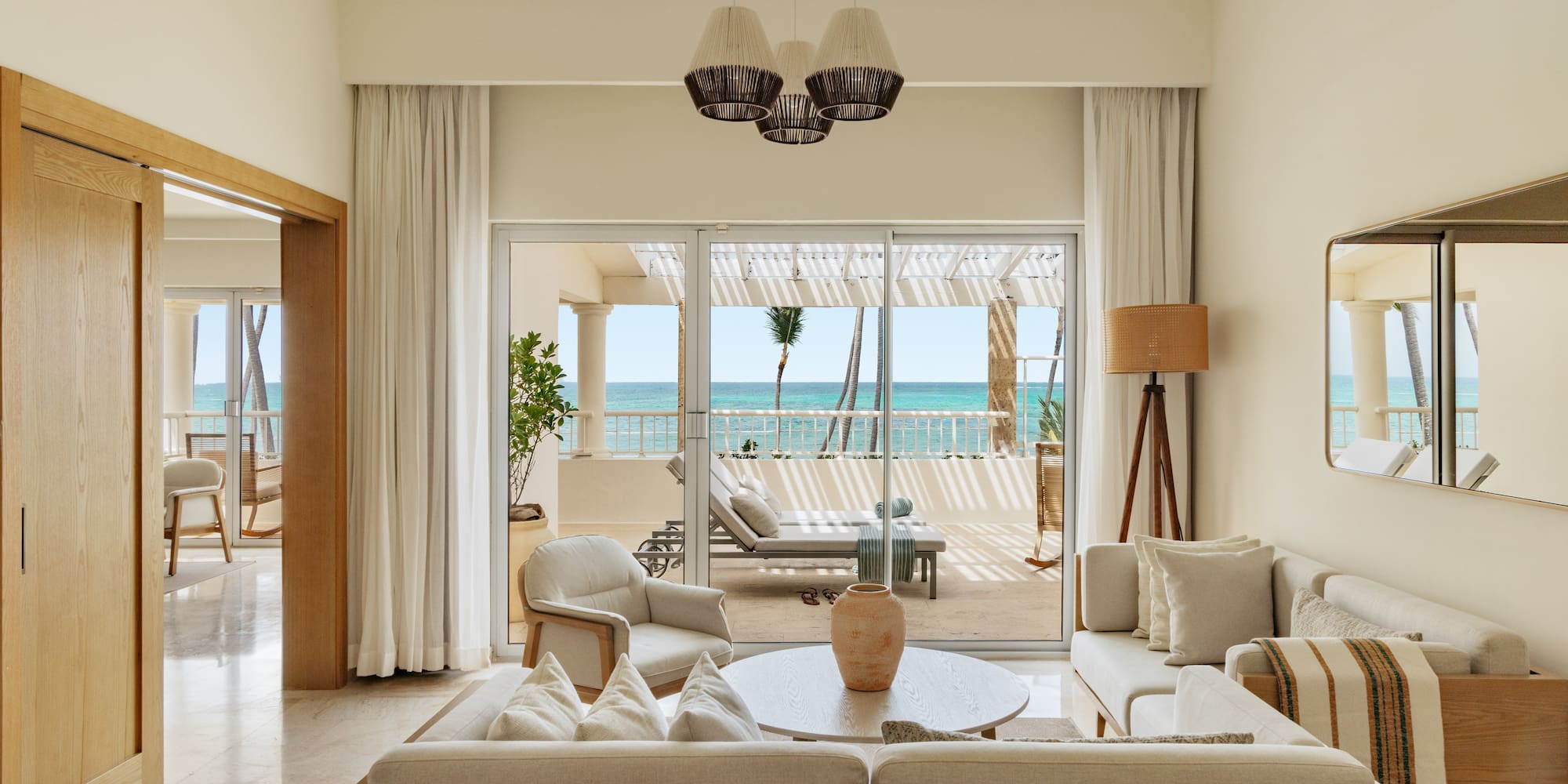 Luxury suite living room with ocean view balcony and tropical palms.