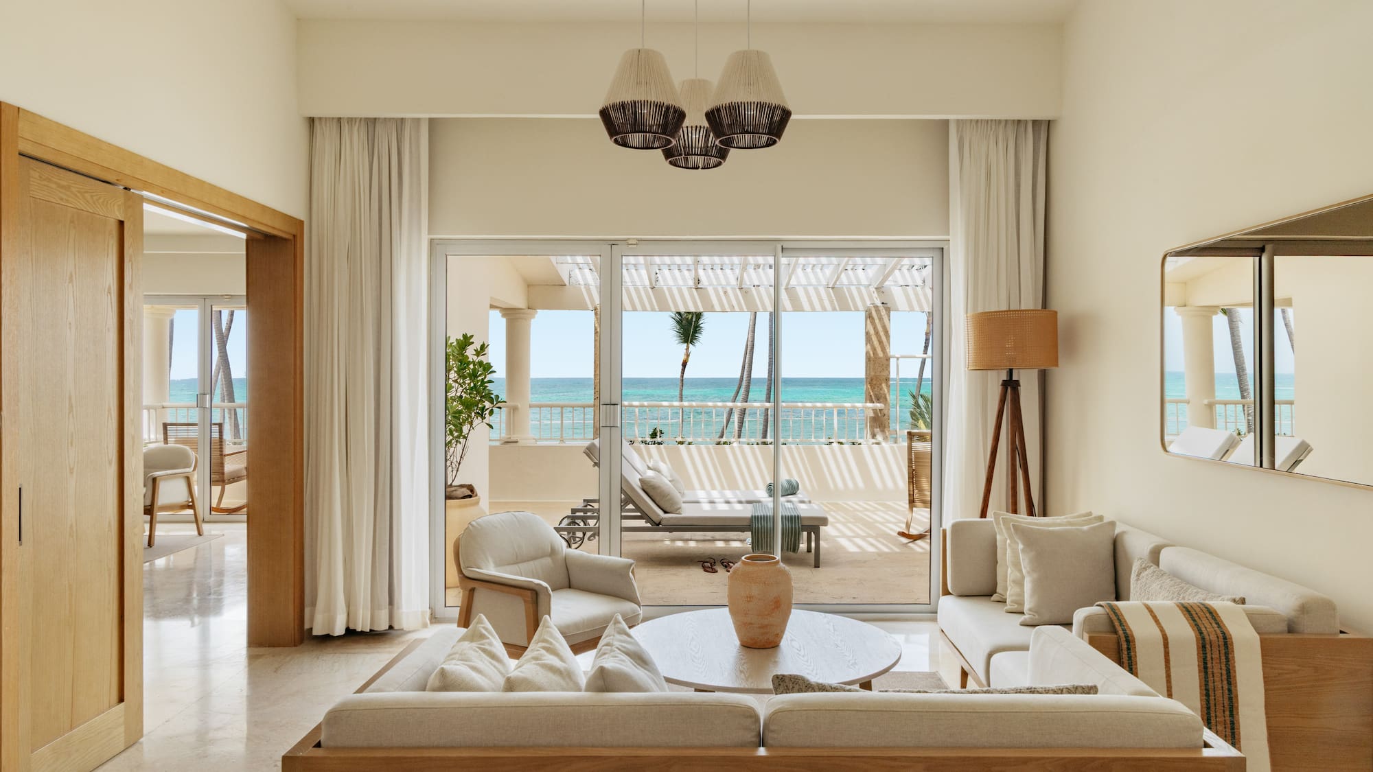 Luxury suite living room with ocean view balcony and tropical palms.
