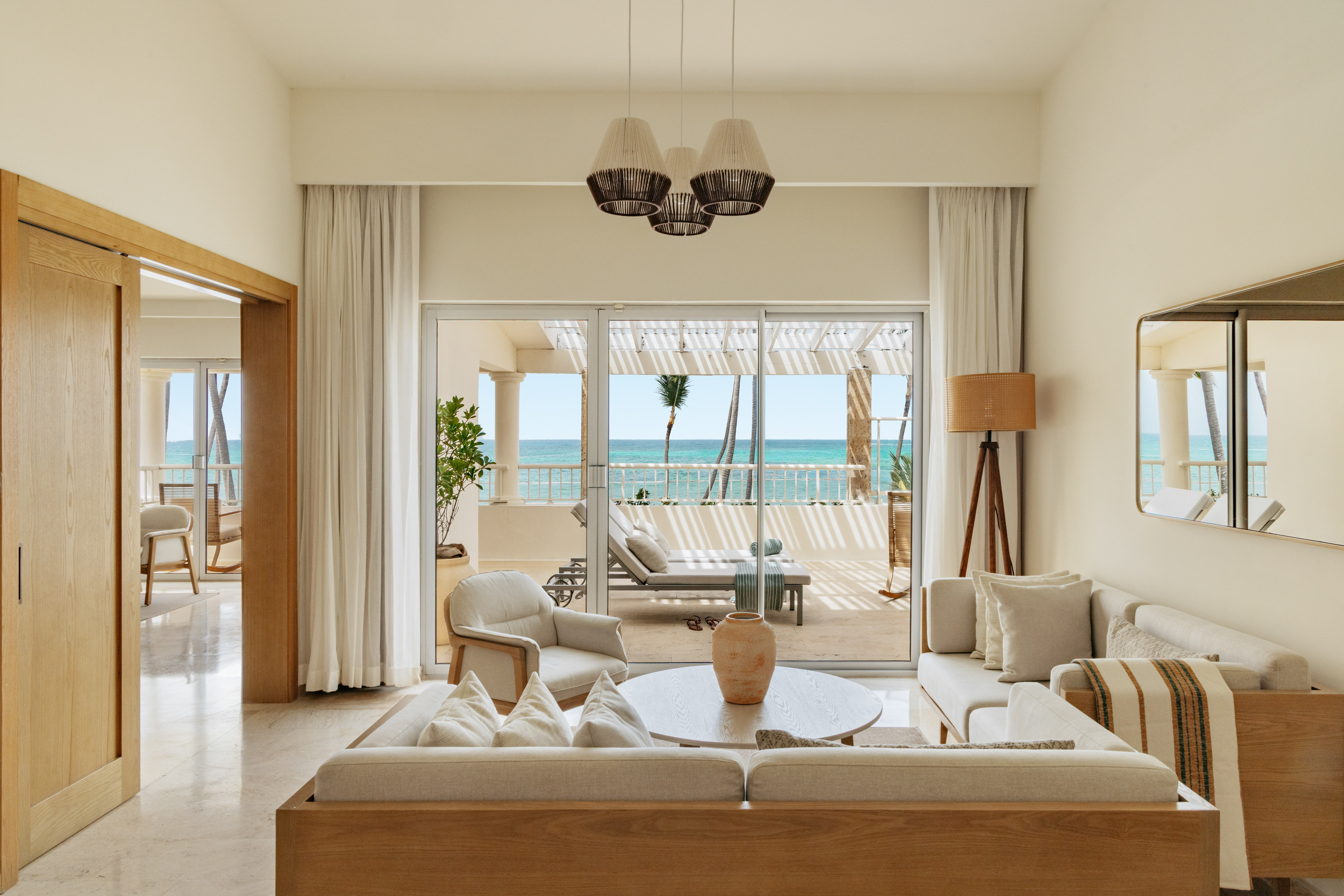 Luxury suite living room with ocean view balcony and tropical palms.