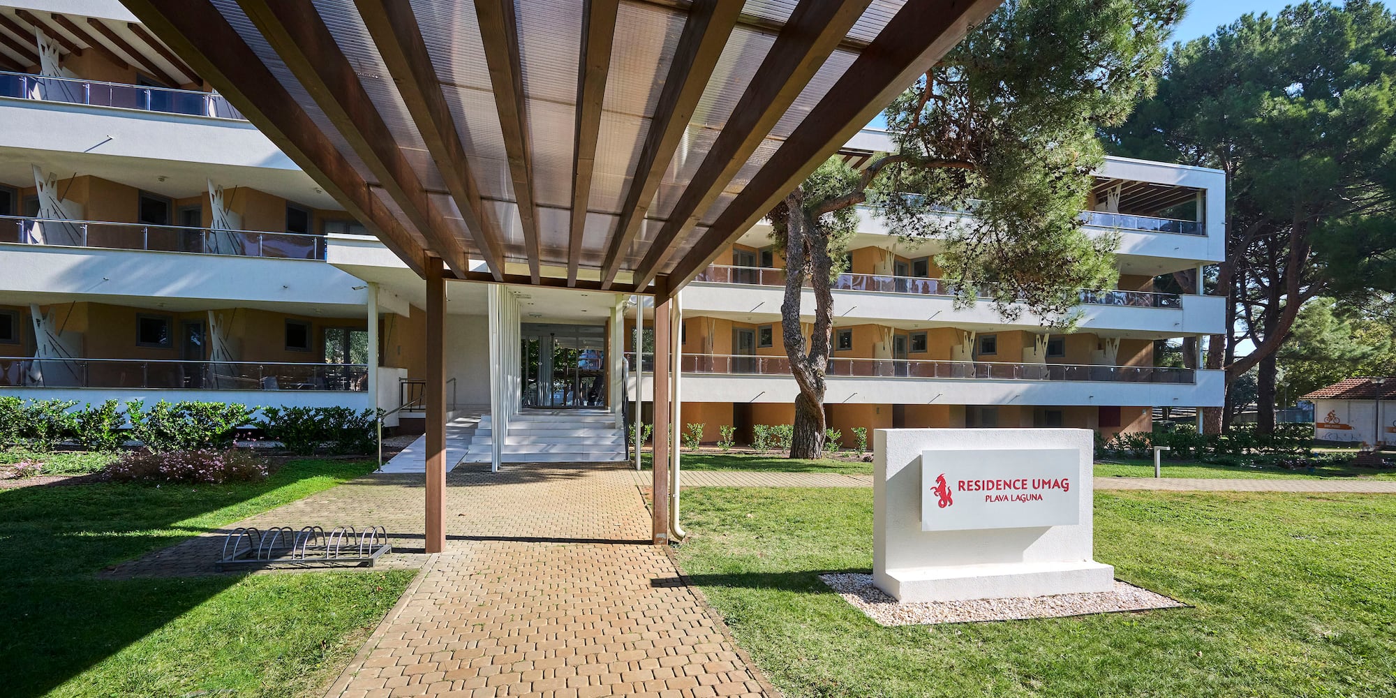 a walkway with a sign and grass in front of a building
